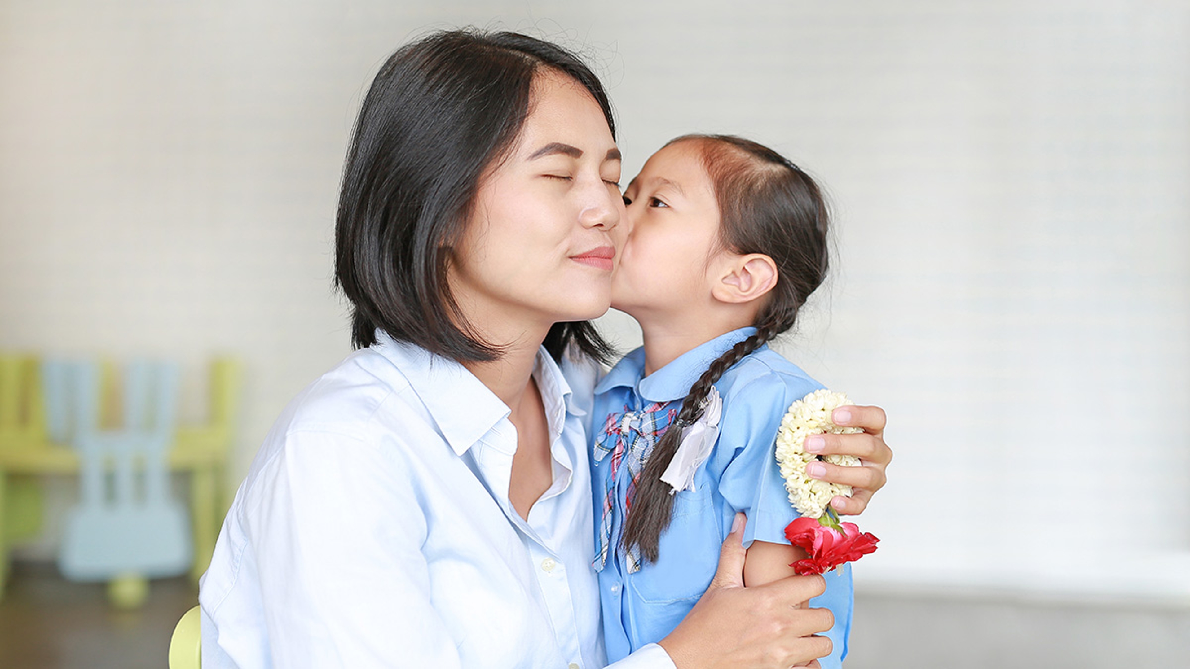 Article Cards Featured Image Portrait Asian little girl kissing her mom and hugging on Mother's day in thailand. Kid Pay respect and give Thai traditional jasmine garland to mother.