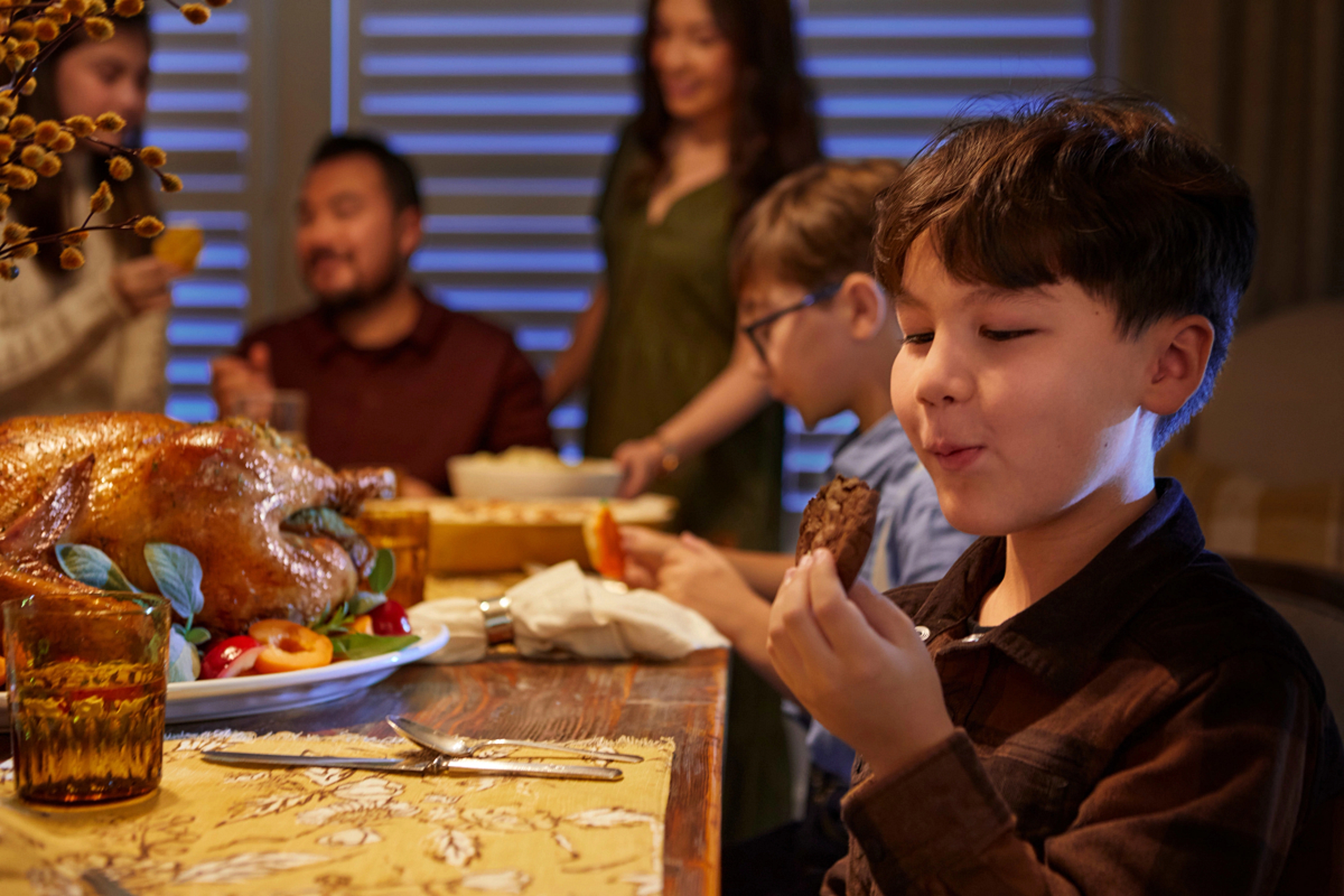 Child eating a cookie at a Thanksgiving table with other people.