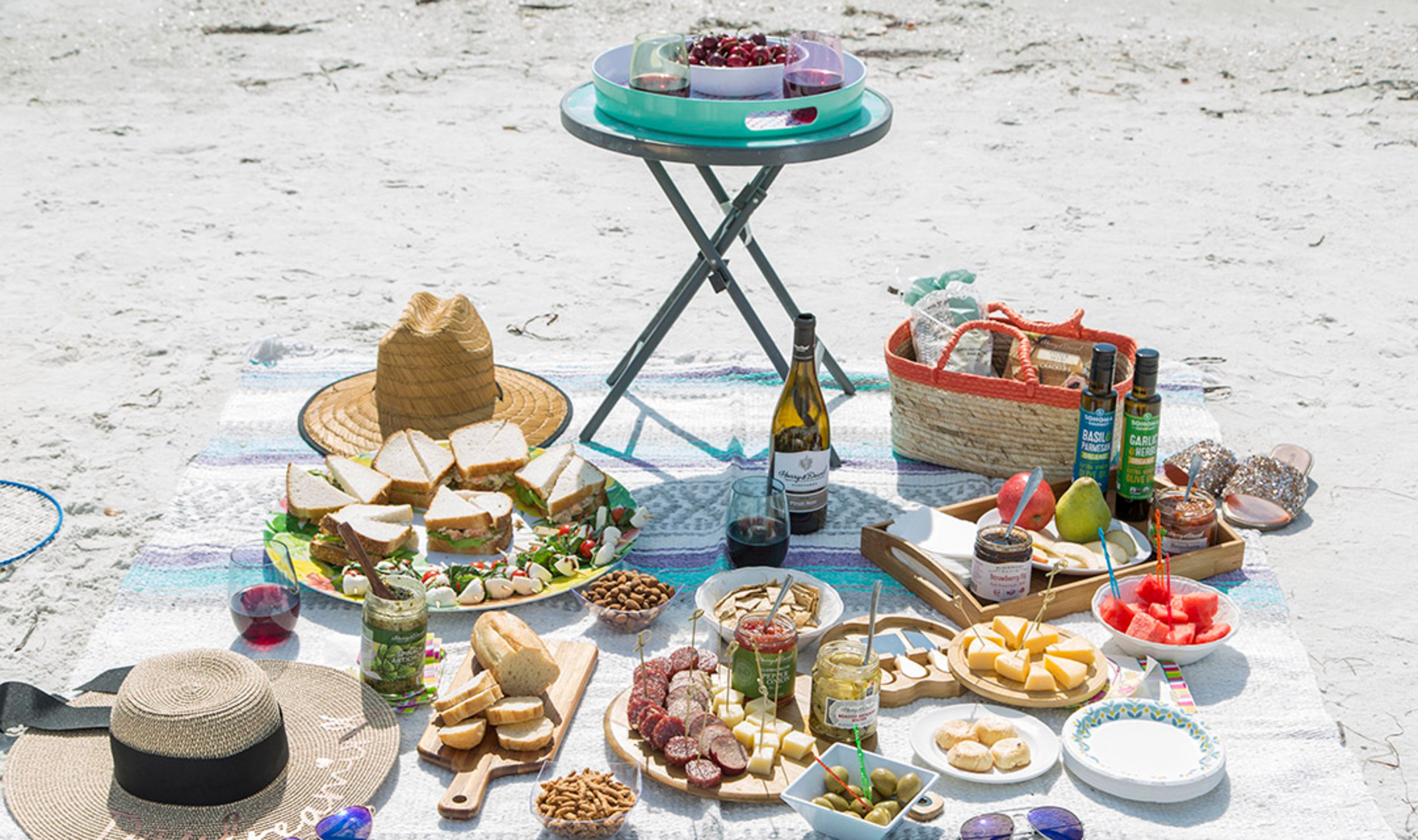 Picnic on the beach featuring products from Harry & David, sandwiches, fruits, charcuterie boards, wine, relish, crackers