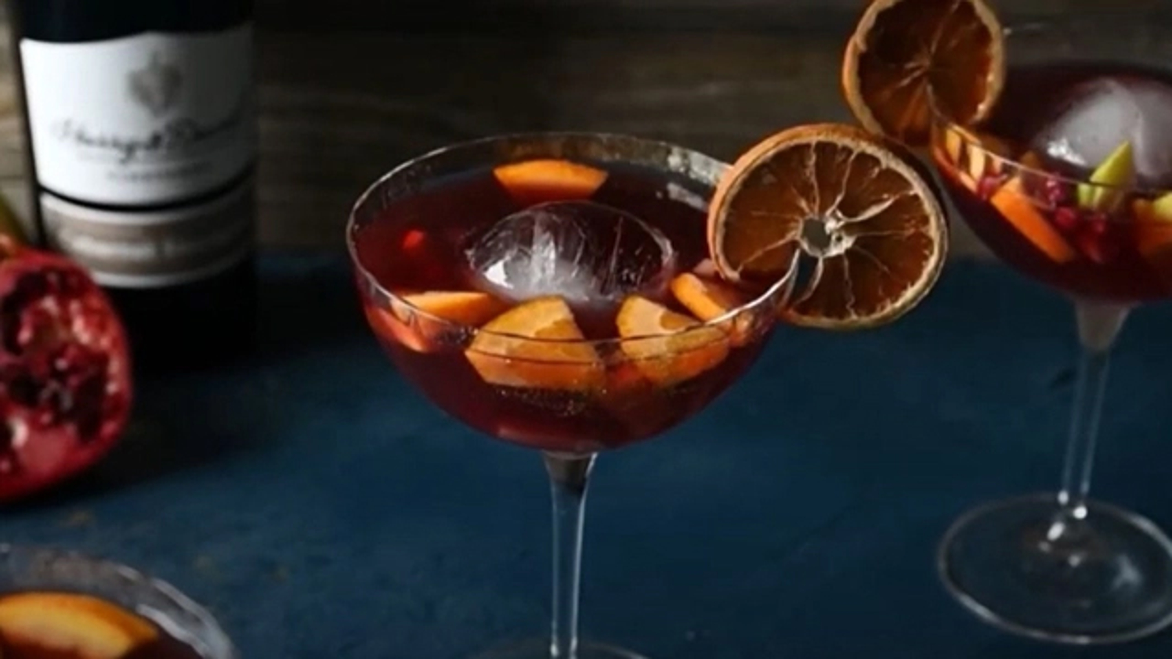 Glass of pomegranate punch with sliced oranges.