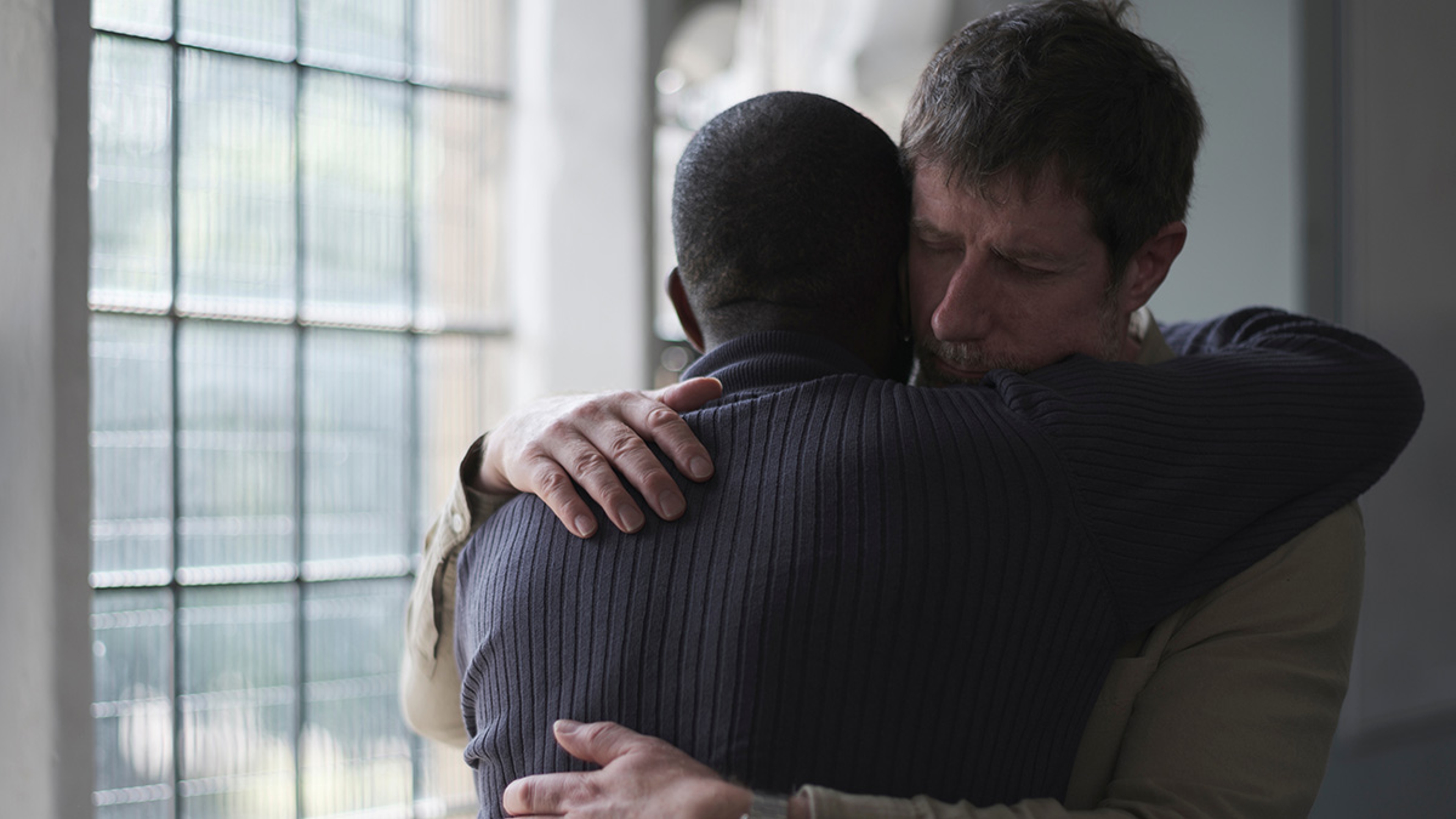 To men hugging and comforting each other.