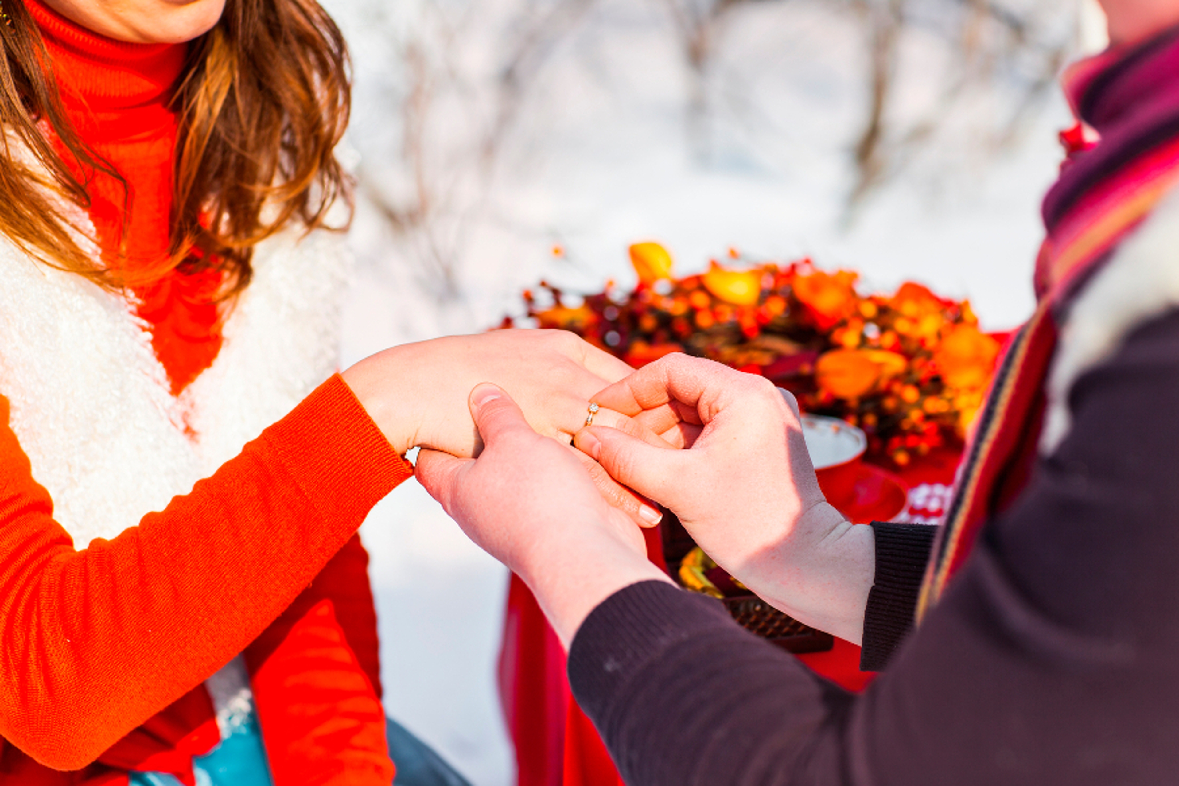 Article Cards Featured Image man putting wedding ring on woman hand. Christmas and New Year decoration   tree, gifts and wedding bouquet