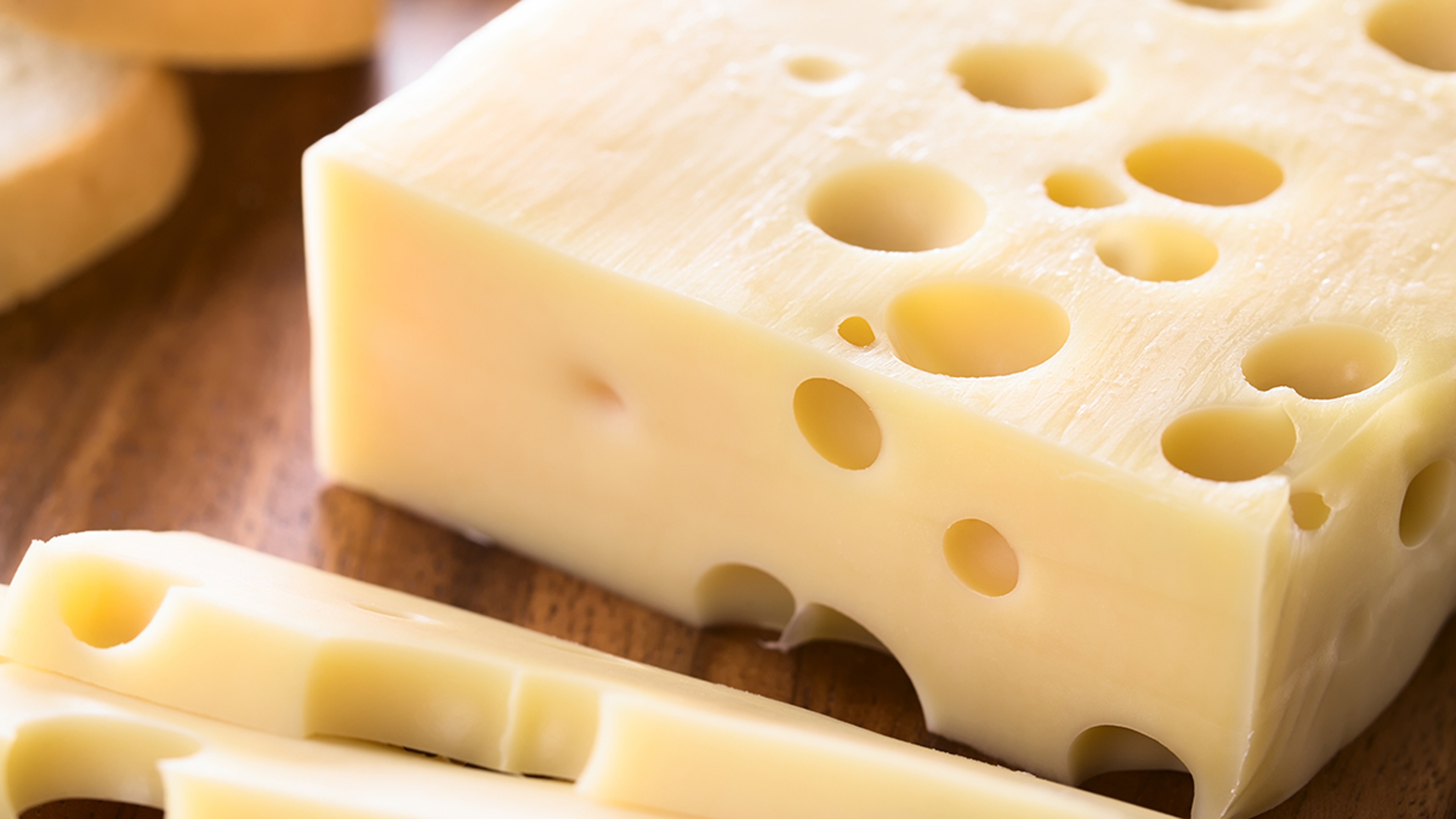 types of cheese piece of Emmental, Emmentaler or Emmenthal cheese on wooden plate