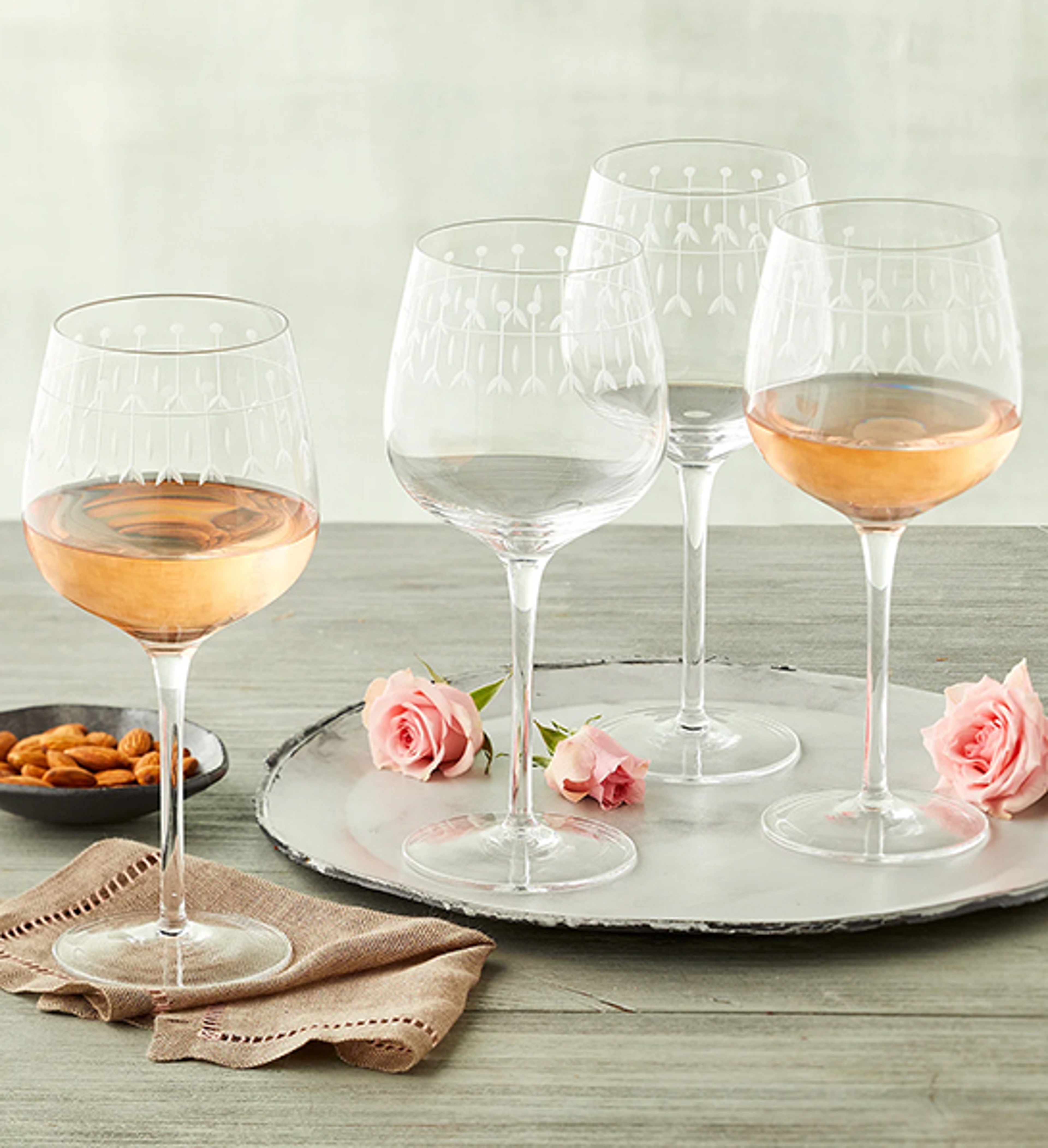 Home bartender with four etched wine glasses on a serving tray.