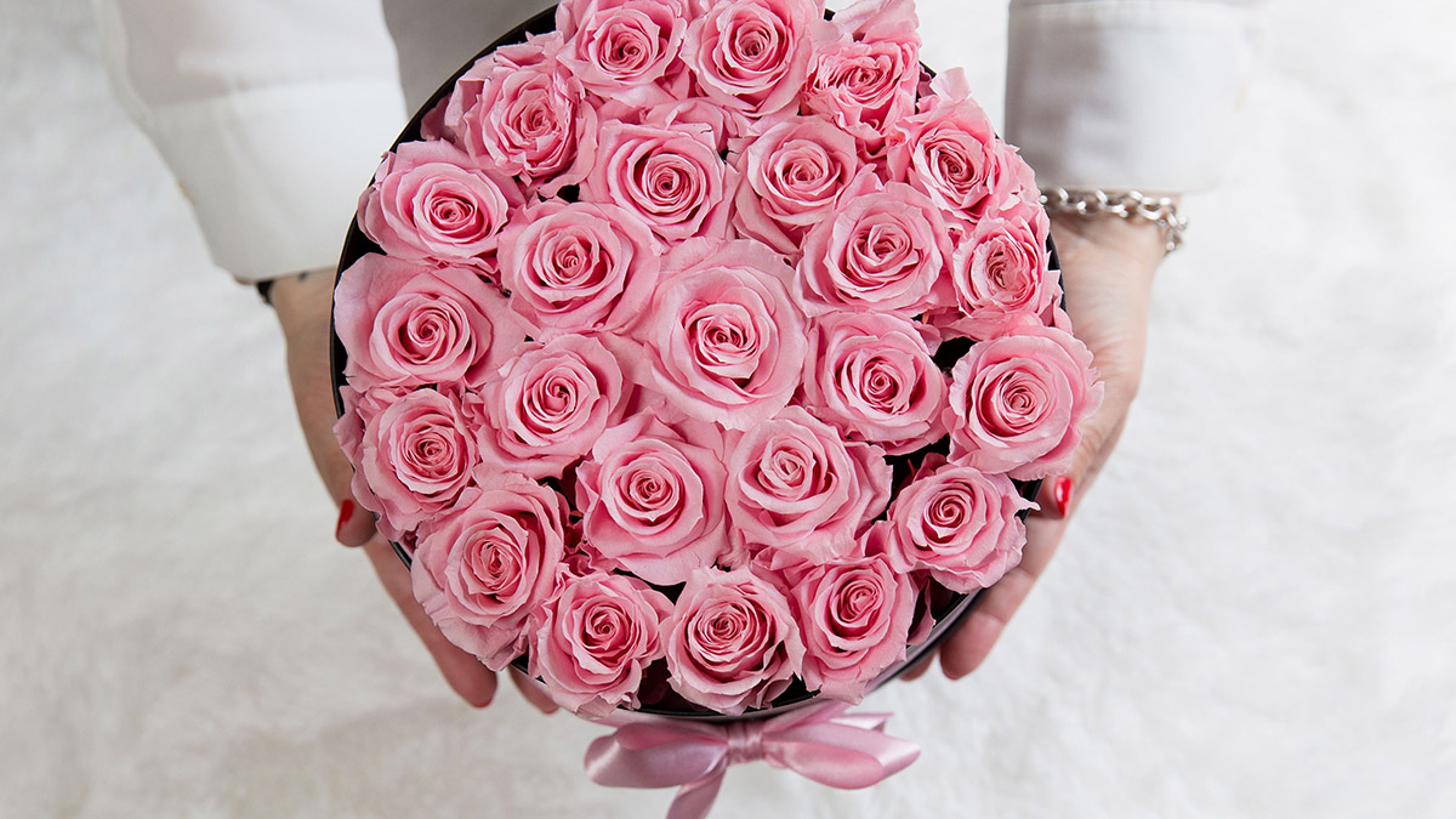 Article Cards Featured Image preserved roses woman holding open box of pink roses above view