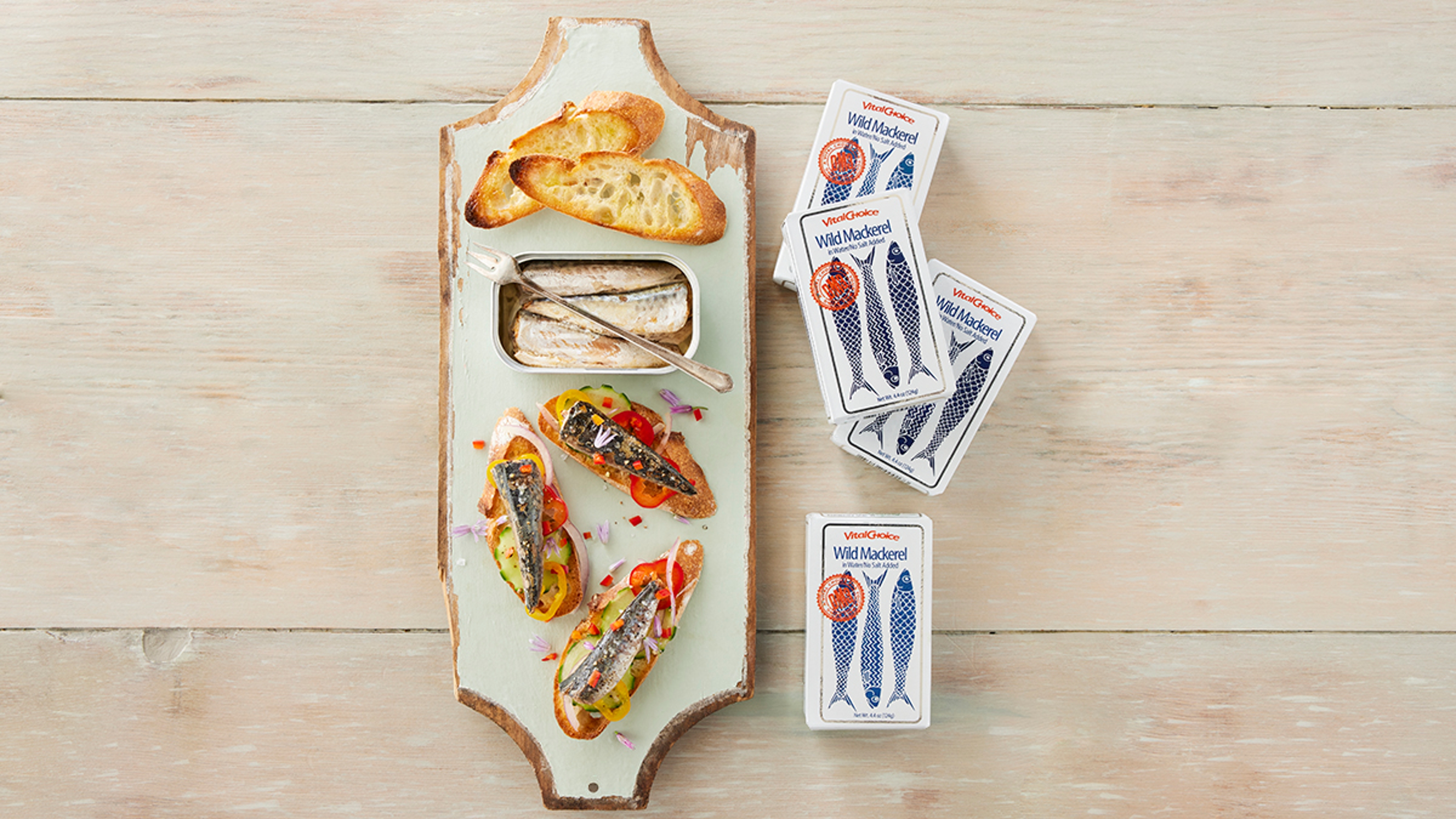 Boxes of tinned mackerel next to a board of mackerel on toast.