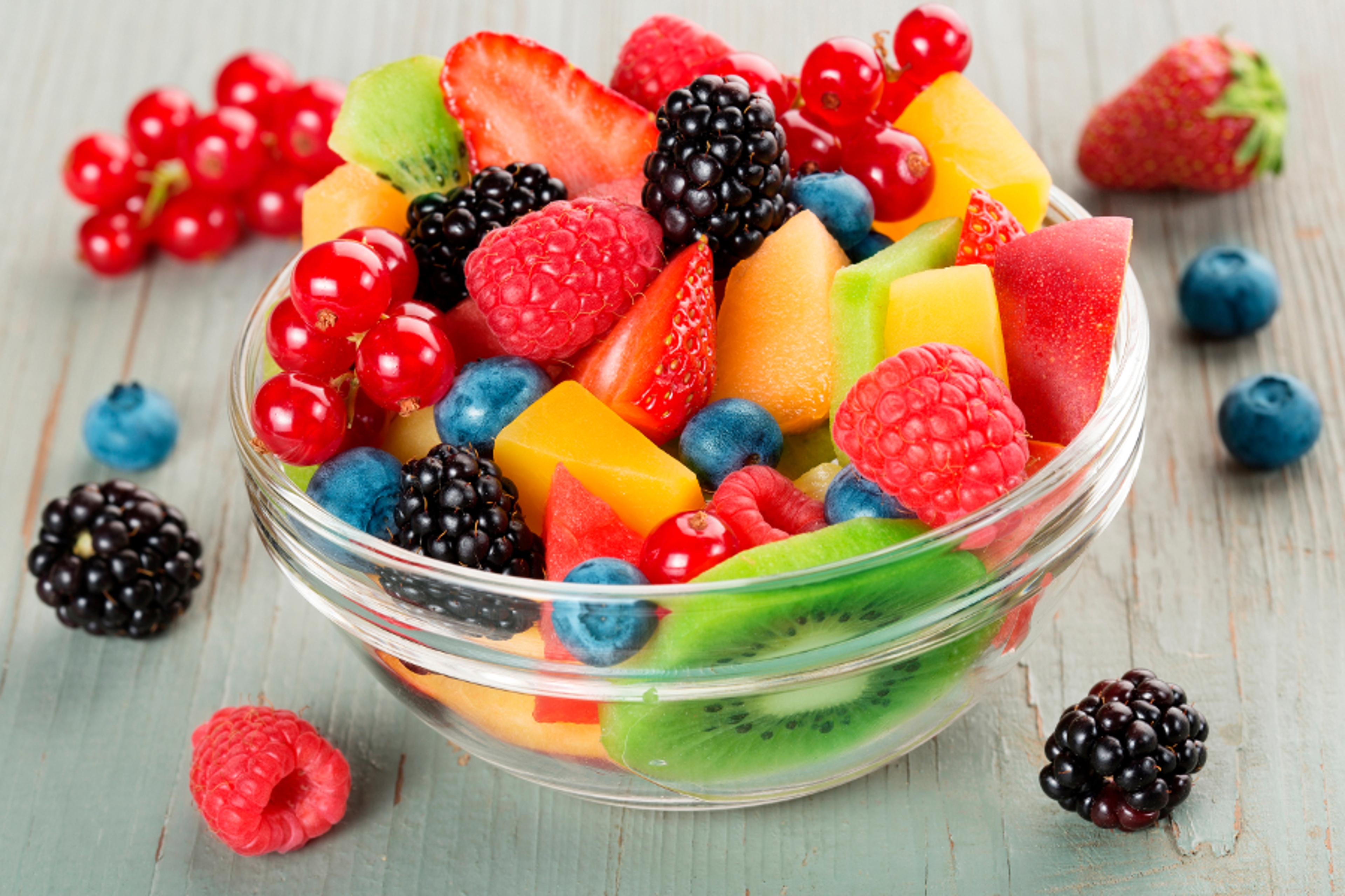 Article Cards Featured Image bowl of fruit cocktail and mixed berries scattered on wooden table