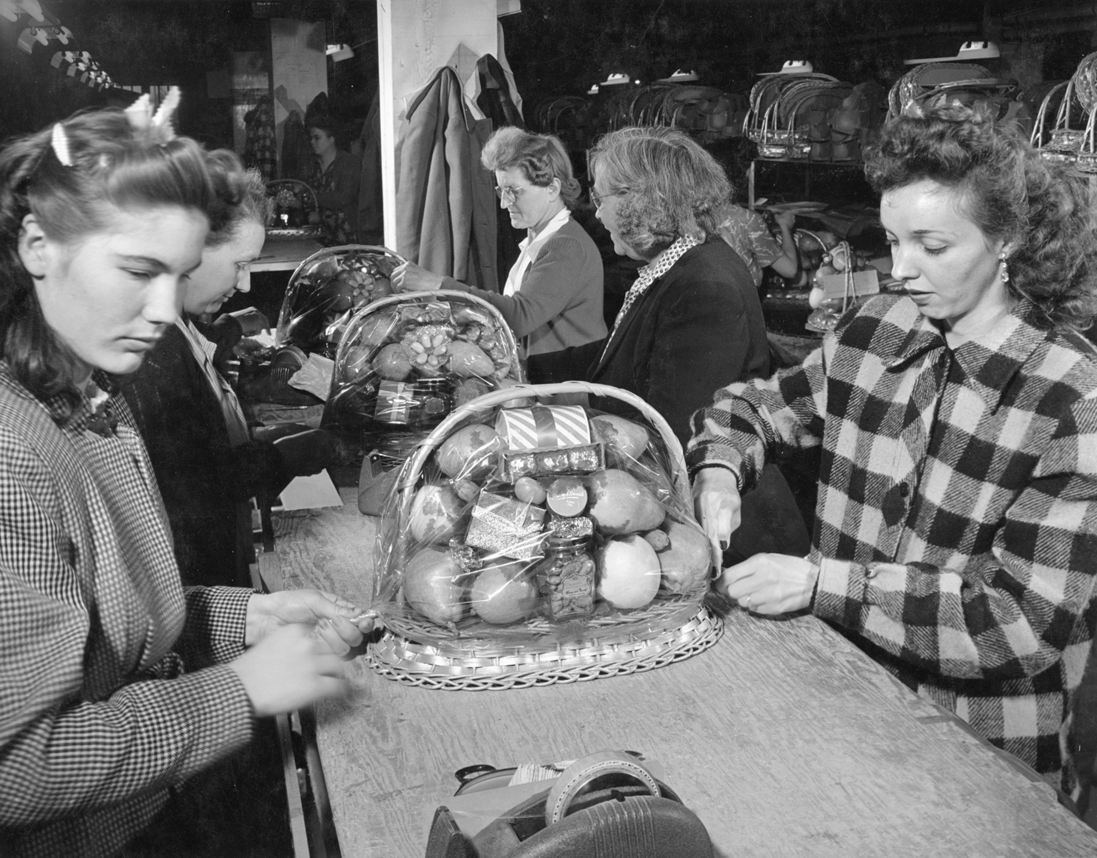 Women wrapping baskets of fruit.