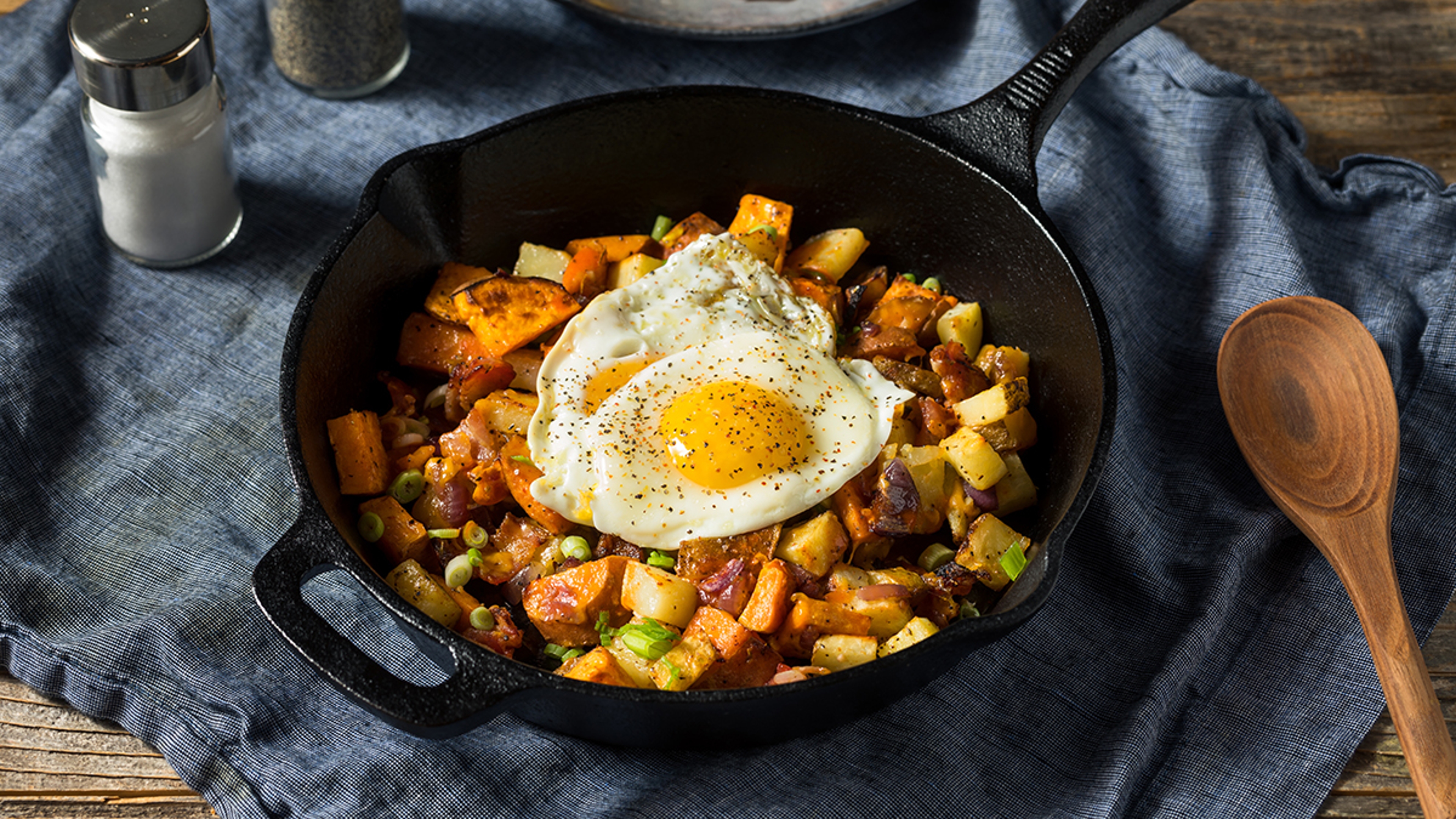 Pan of sweet potato hash topped with fried eggs.