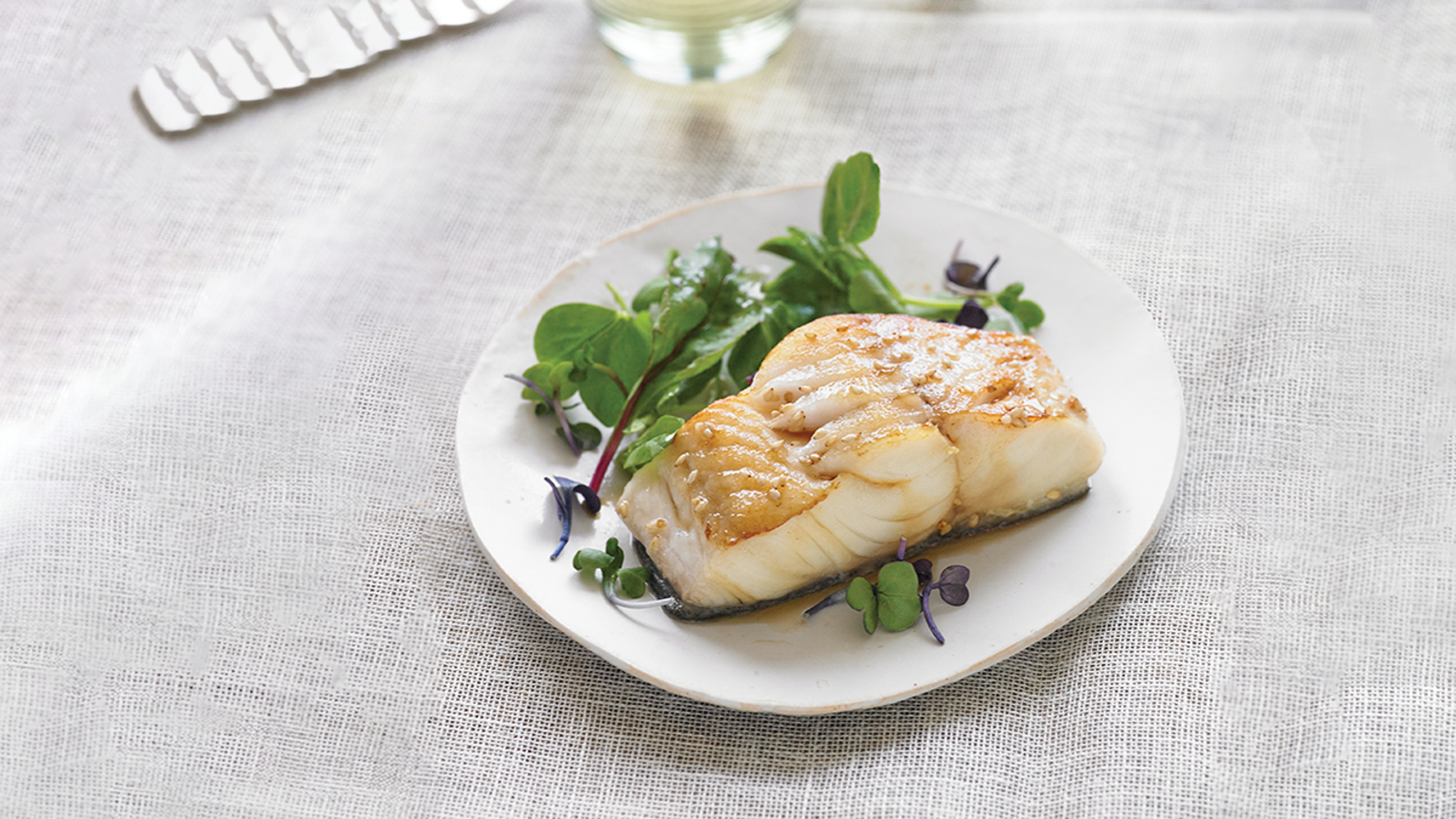 Sablefish filet on plate with vegetables.