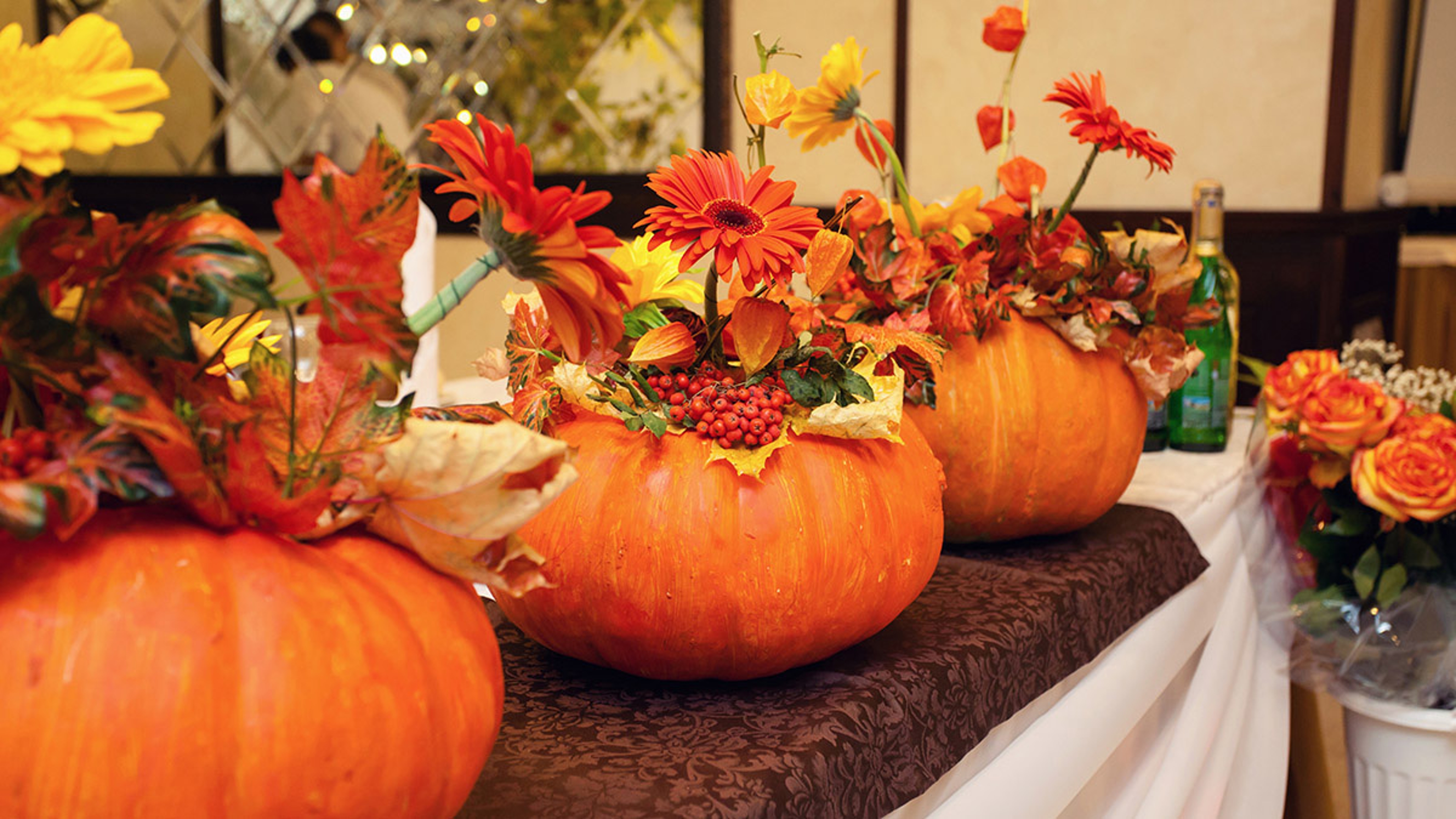 Pumpkins full of fall flowers on a wedding table.