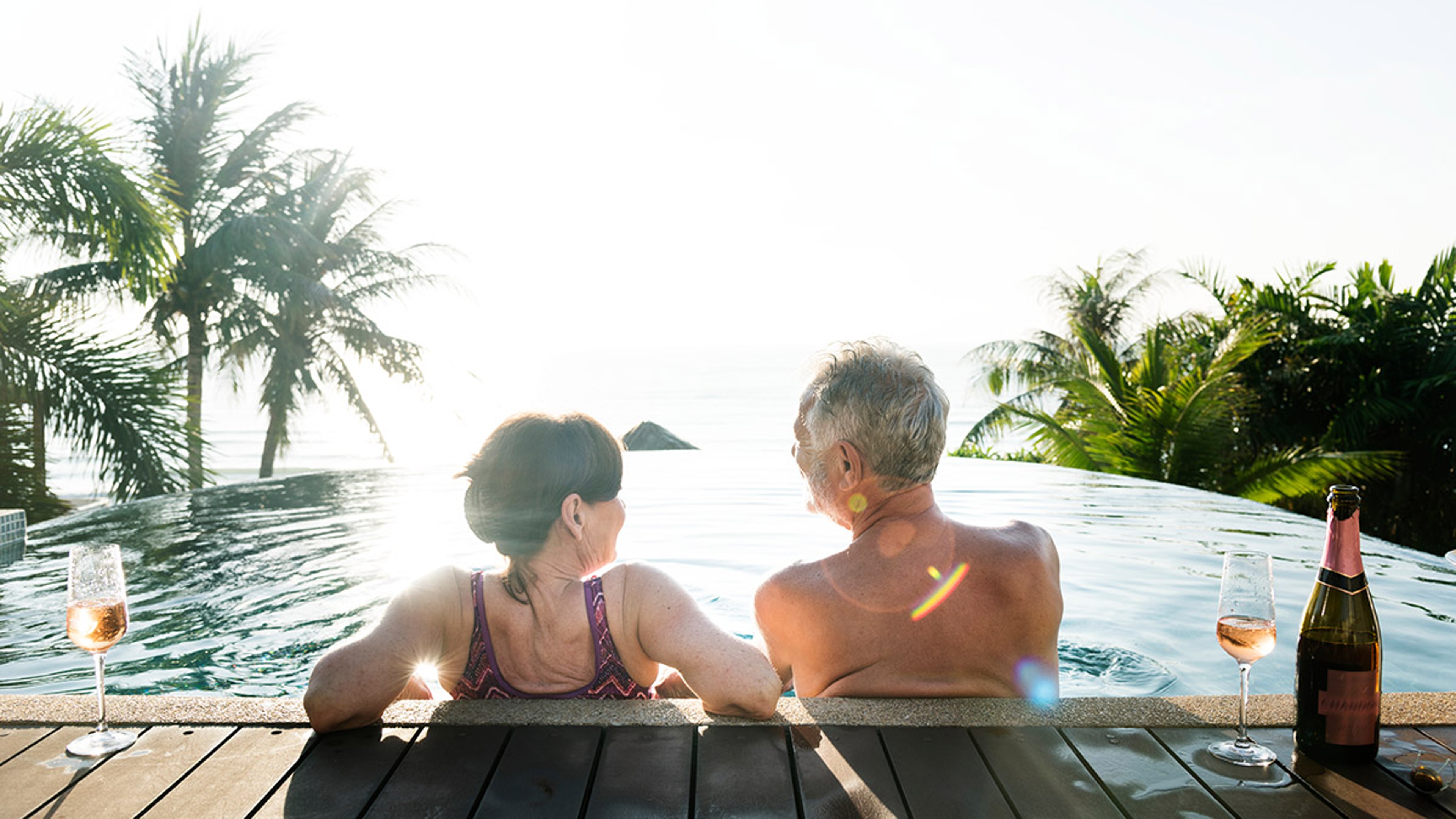 Senior couple drinking prosecco in a swimming pool