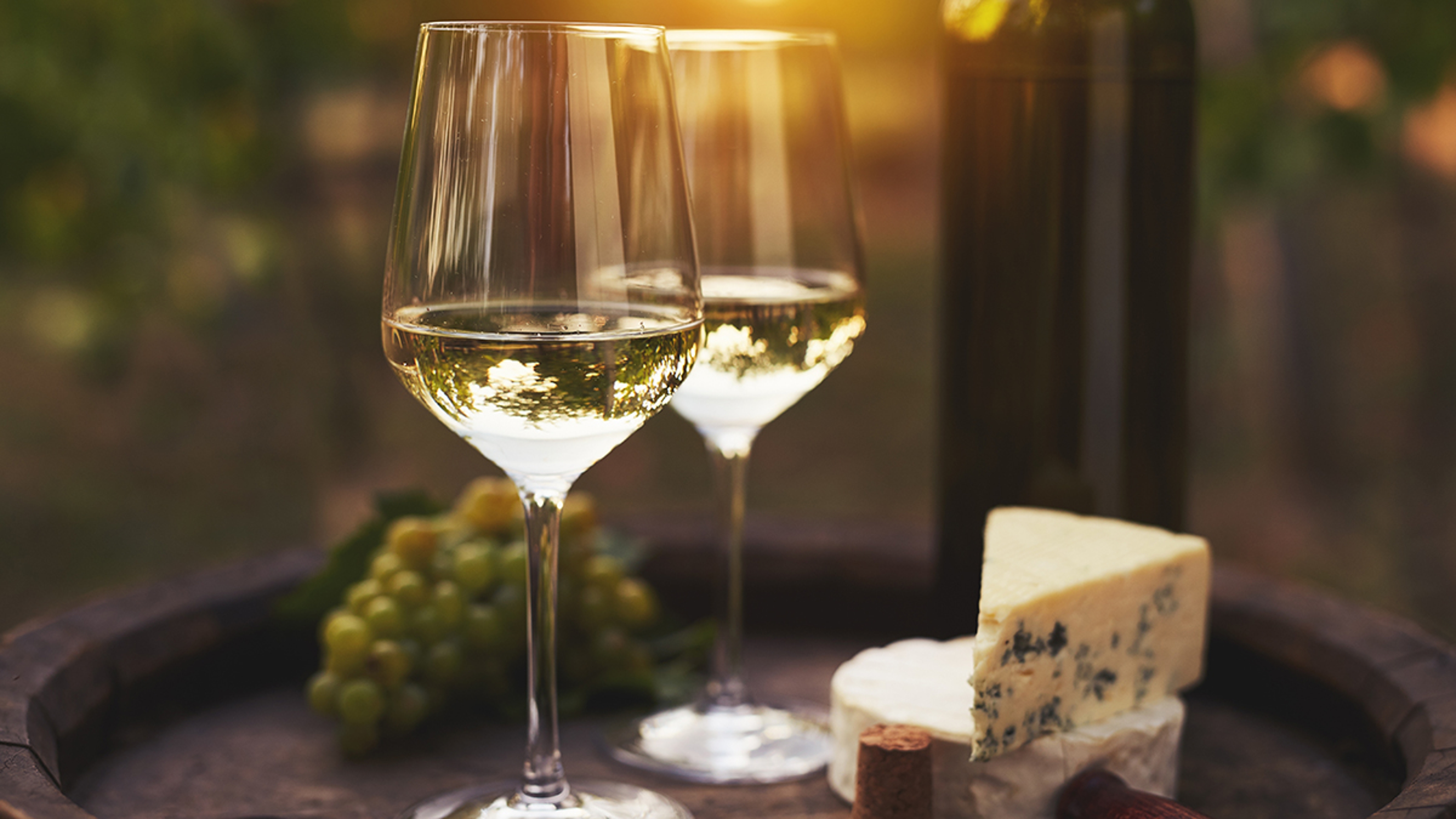 Two glasses of white wine on the old wooden barrel outdoors. Sun