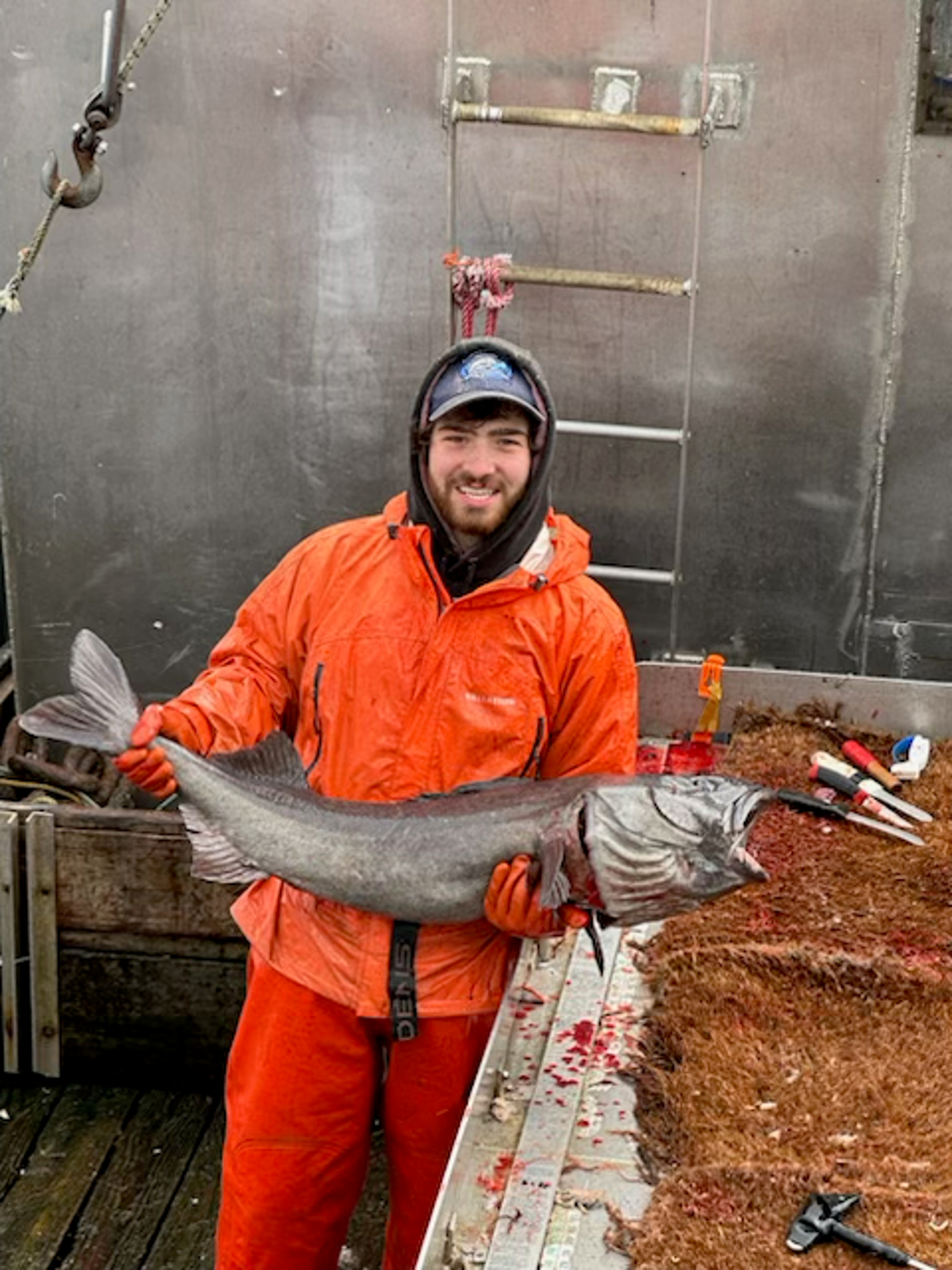 Matthew Blake holding a large sablefish on a boat.