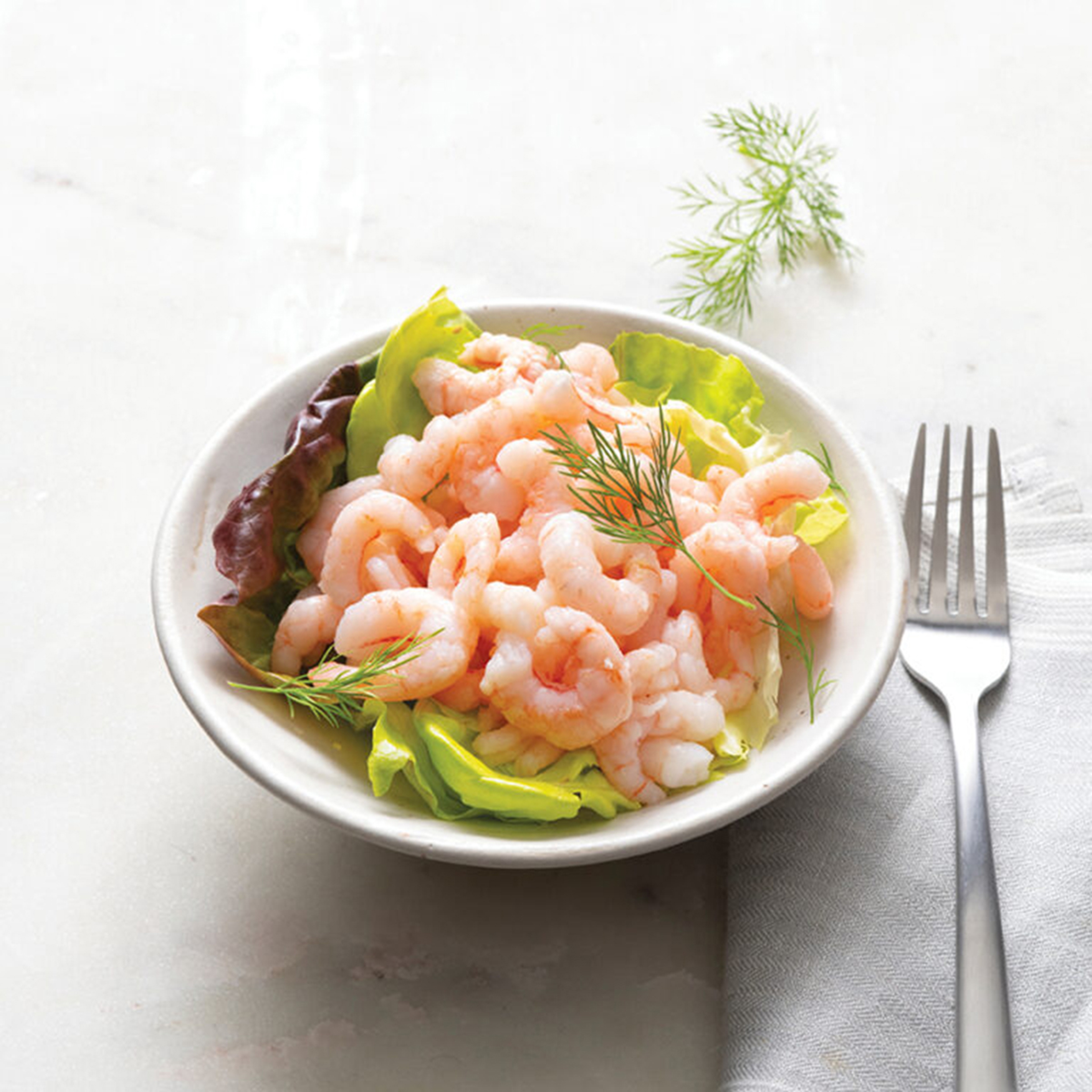 pink shrimp atop lettuce in bowl