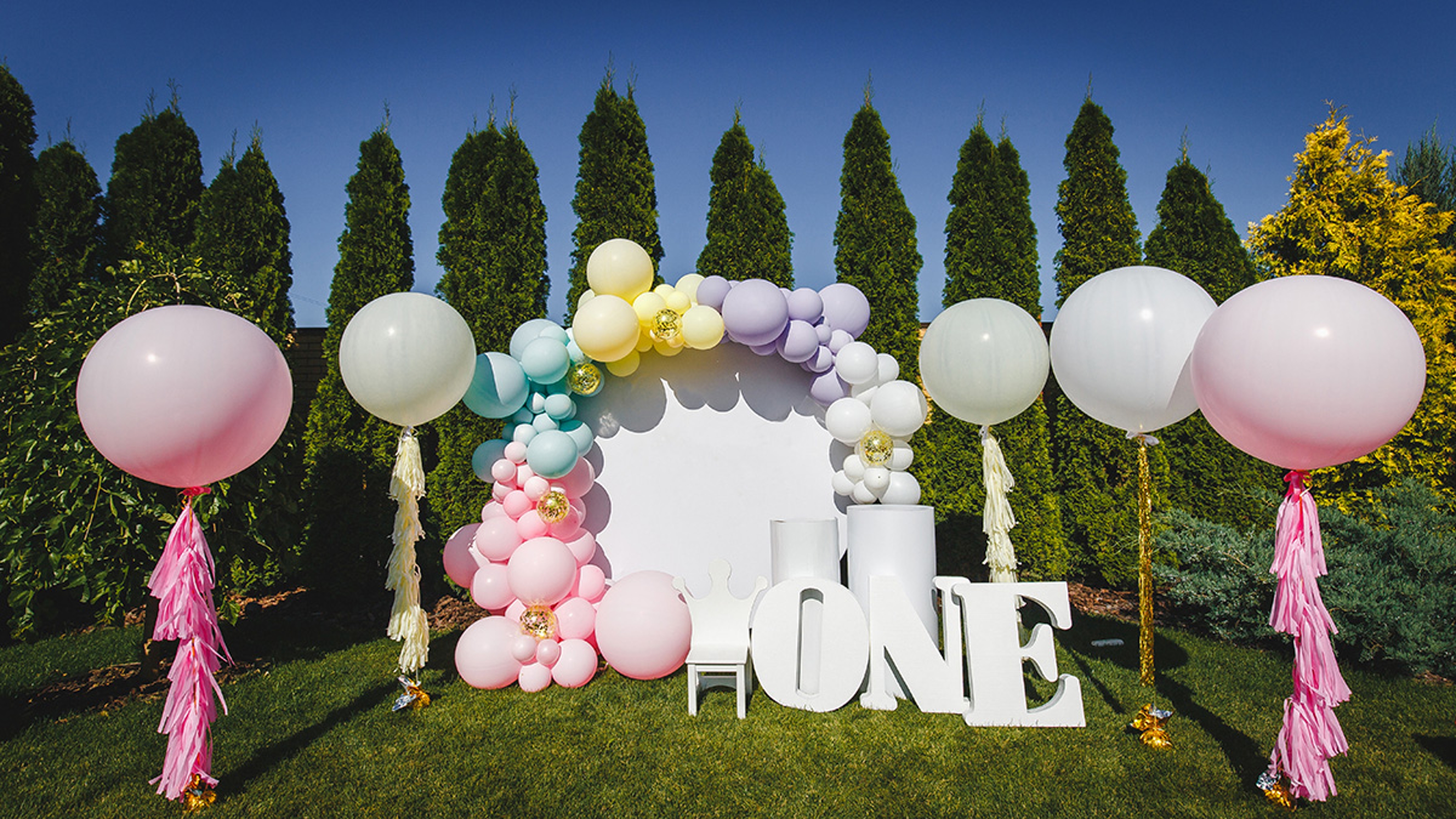 Outdoor first birthday party with balloons.