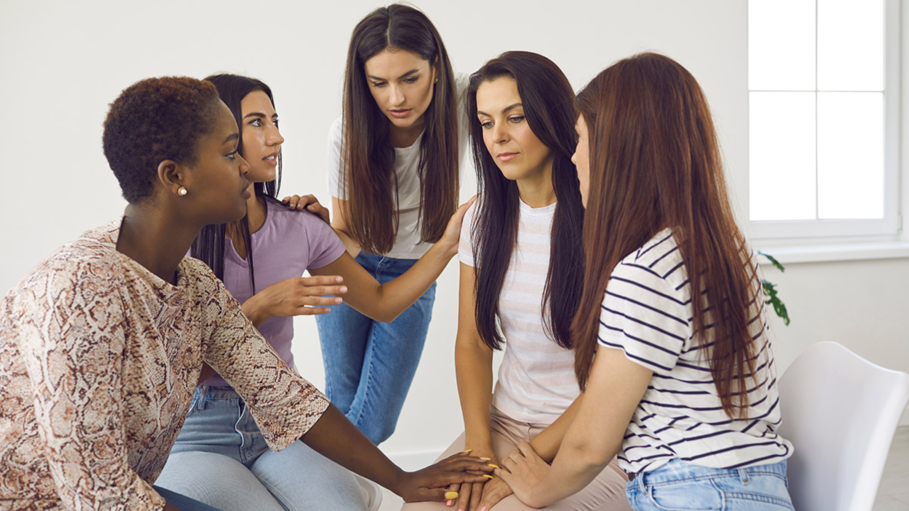 Group of women comforting depressed friend, talking about her problems and supporting her