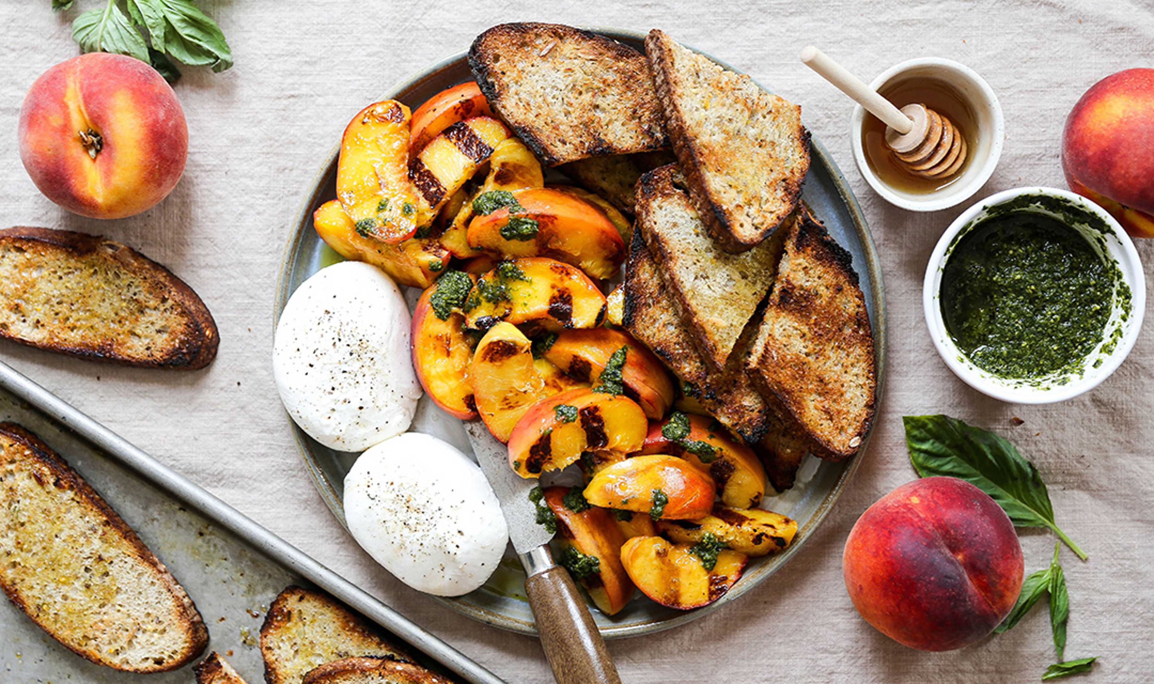 Grilled peaches, burrata and bread on a plate.
