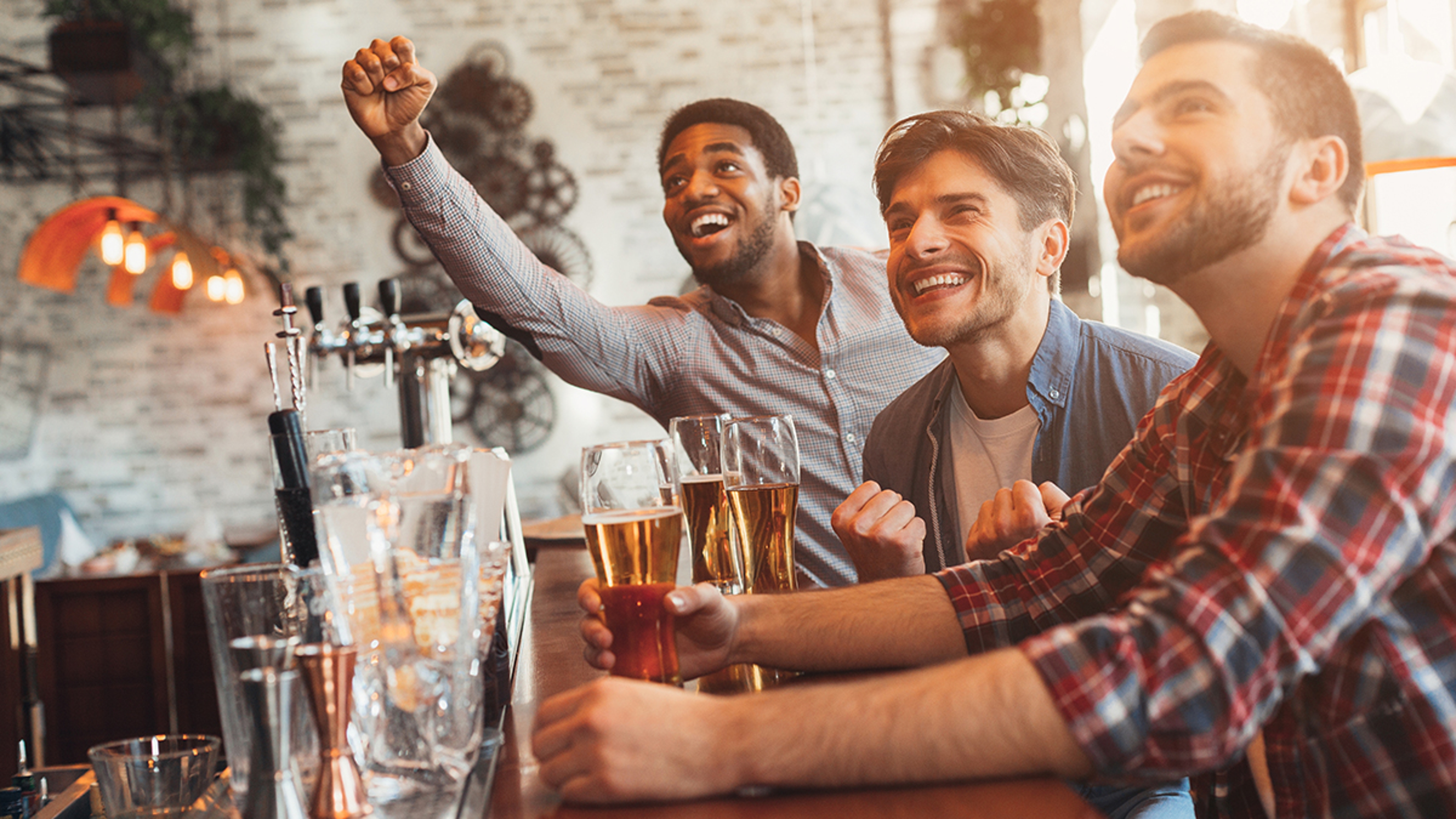 Article Cards Featured Image Watching football in bar. Happy friends drinking beer