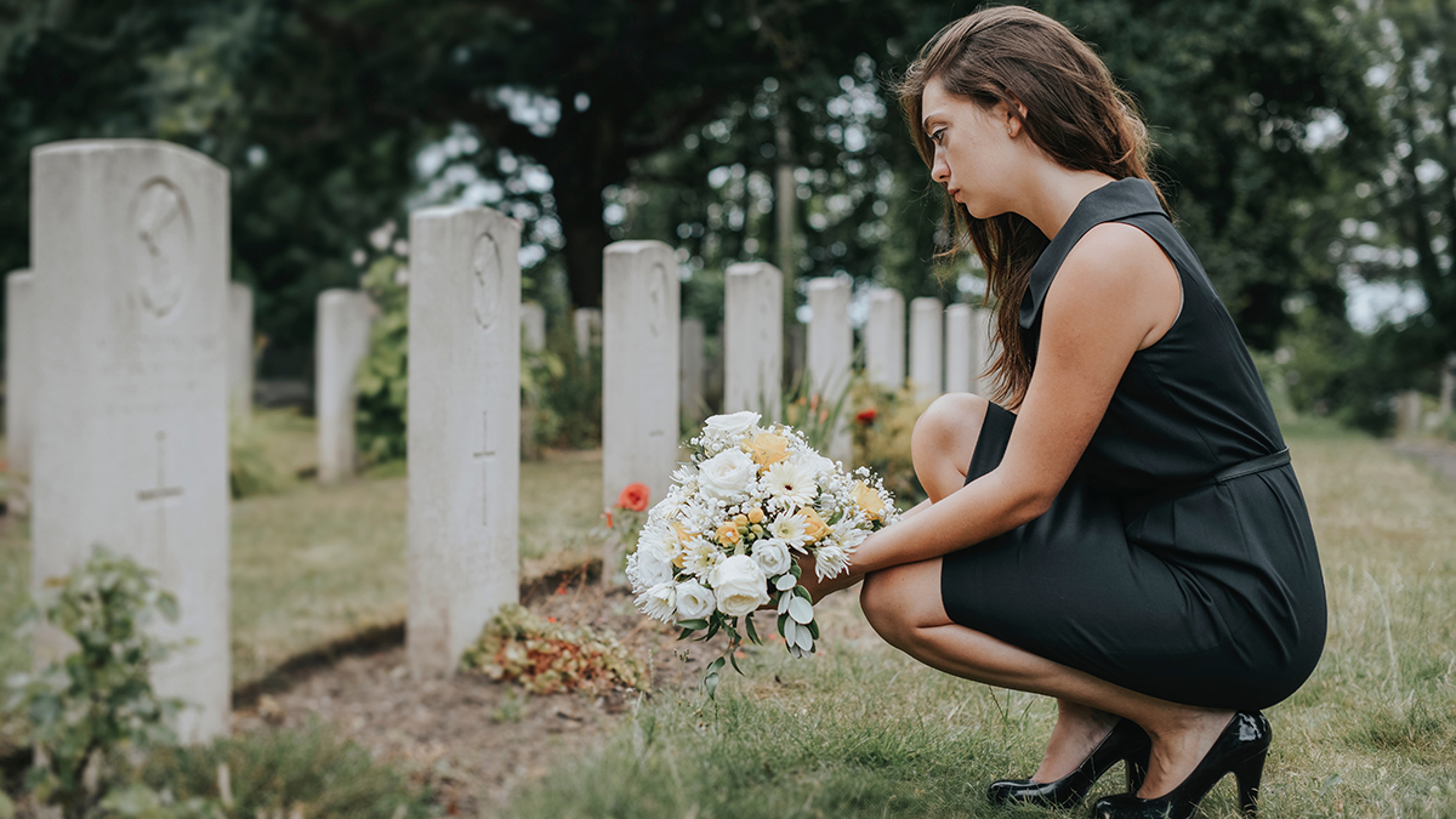 Grief overload with a woman laying flowers on a grave.