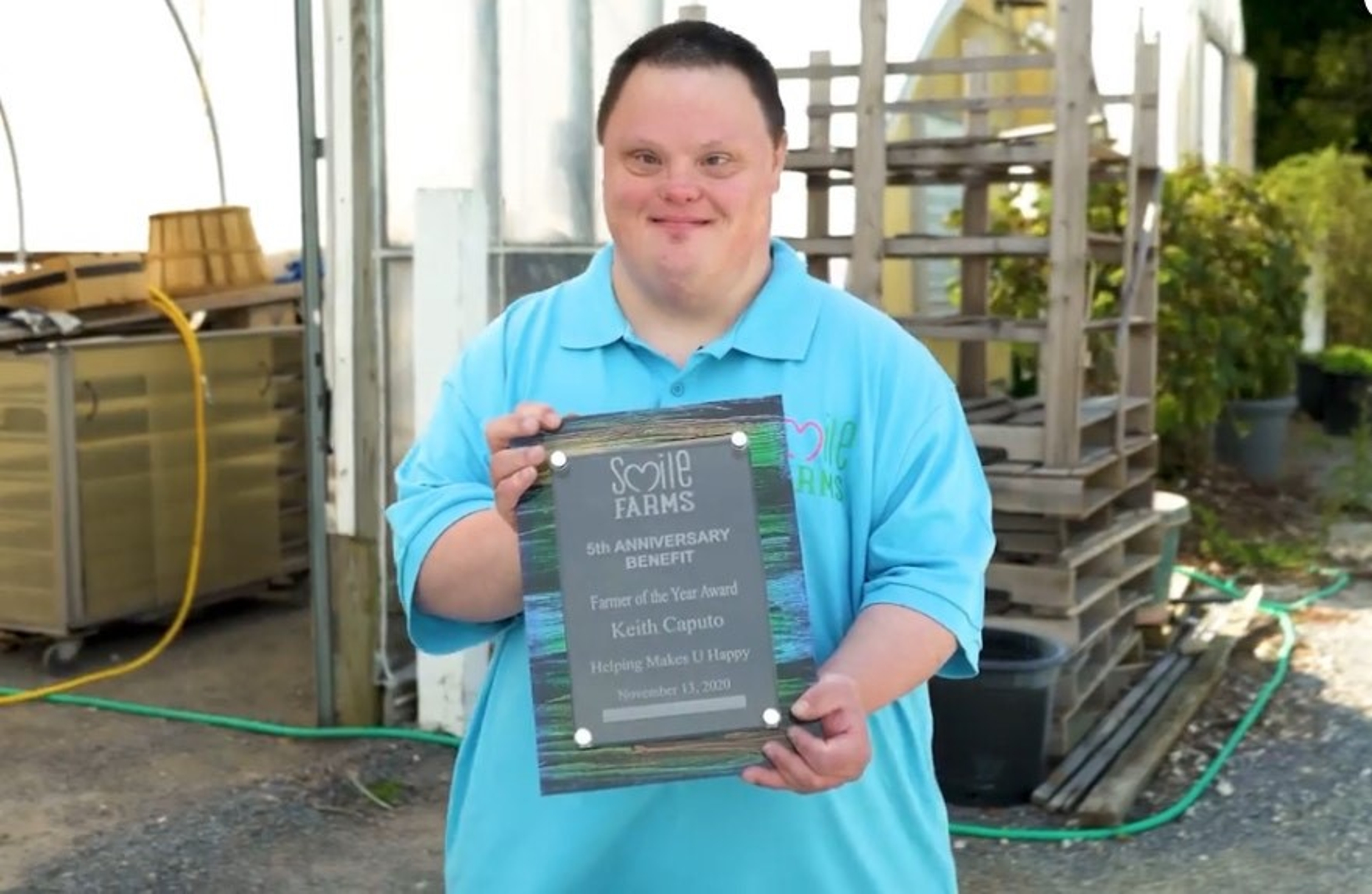 Keith holding a Smile Farms award