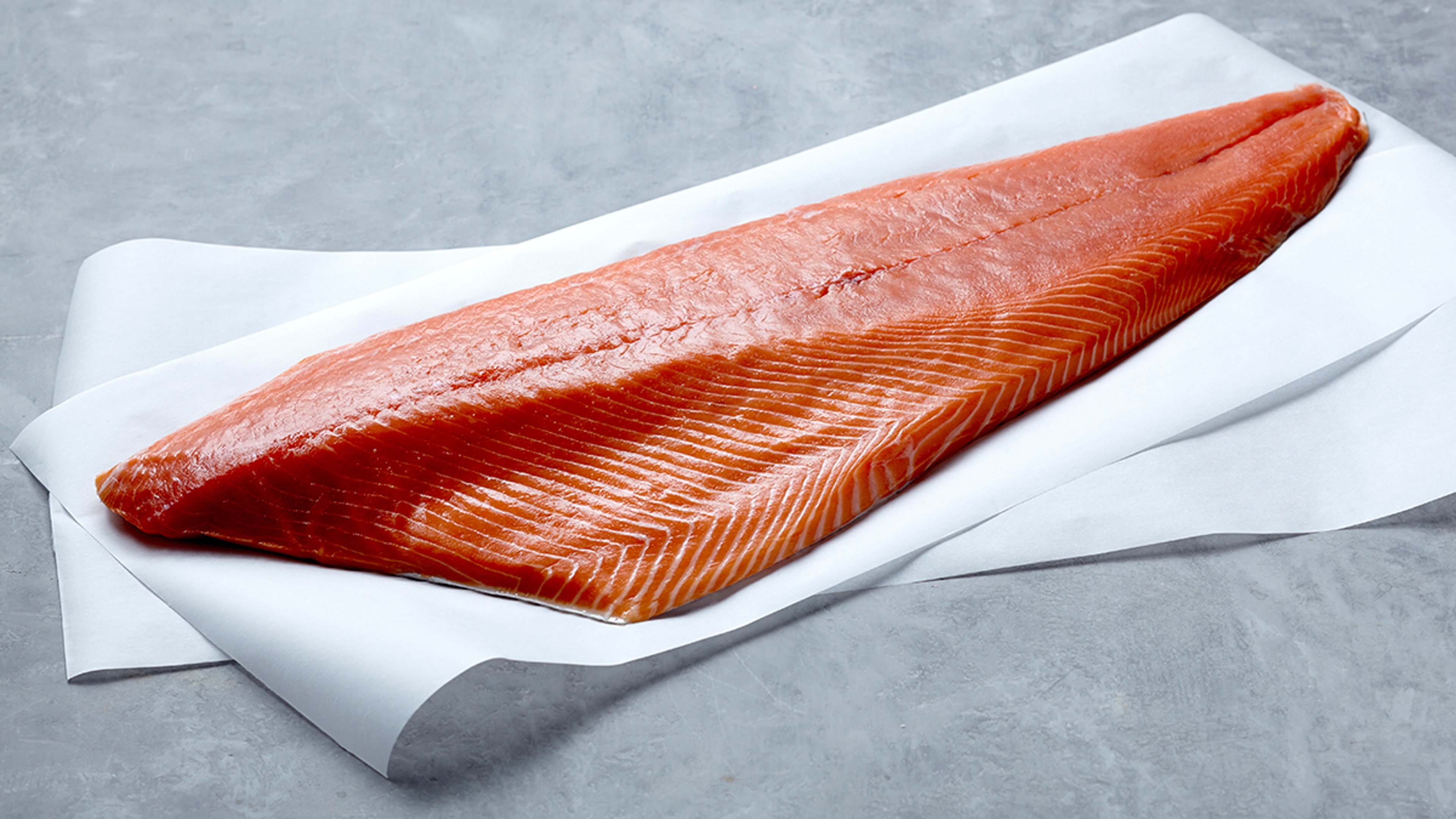 Raw filet of Copper River King salmon on parchment paper.