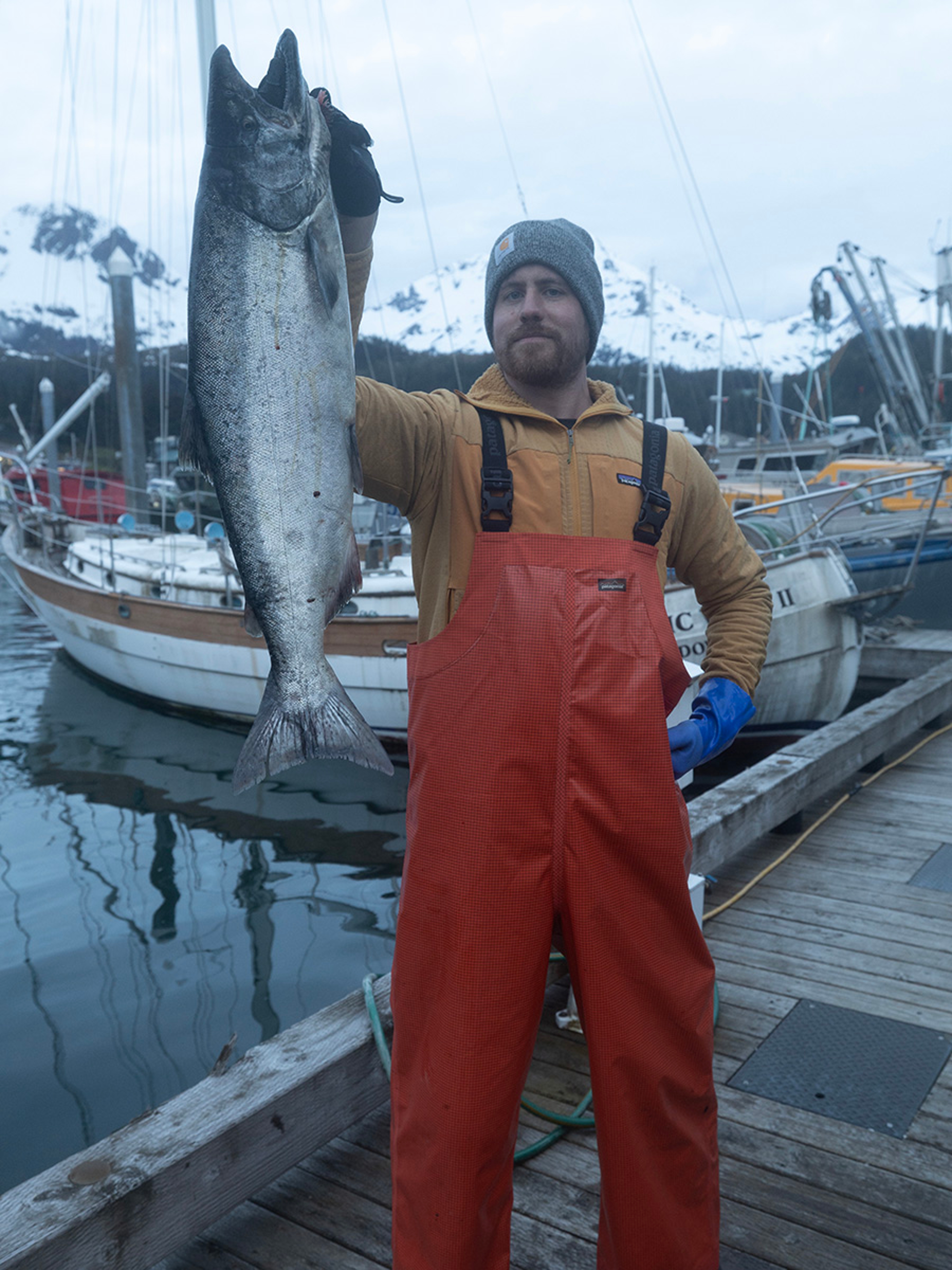 Fisherman holding a salmon on a dock.