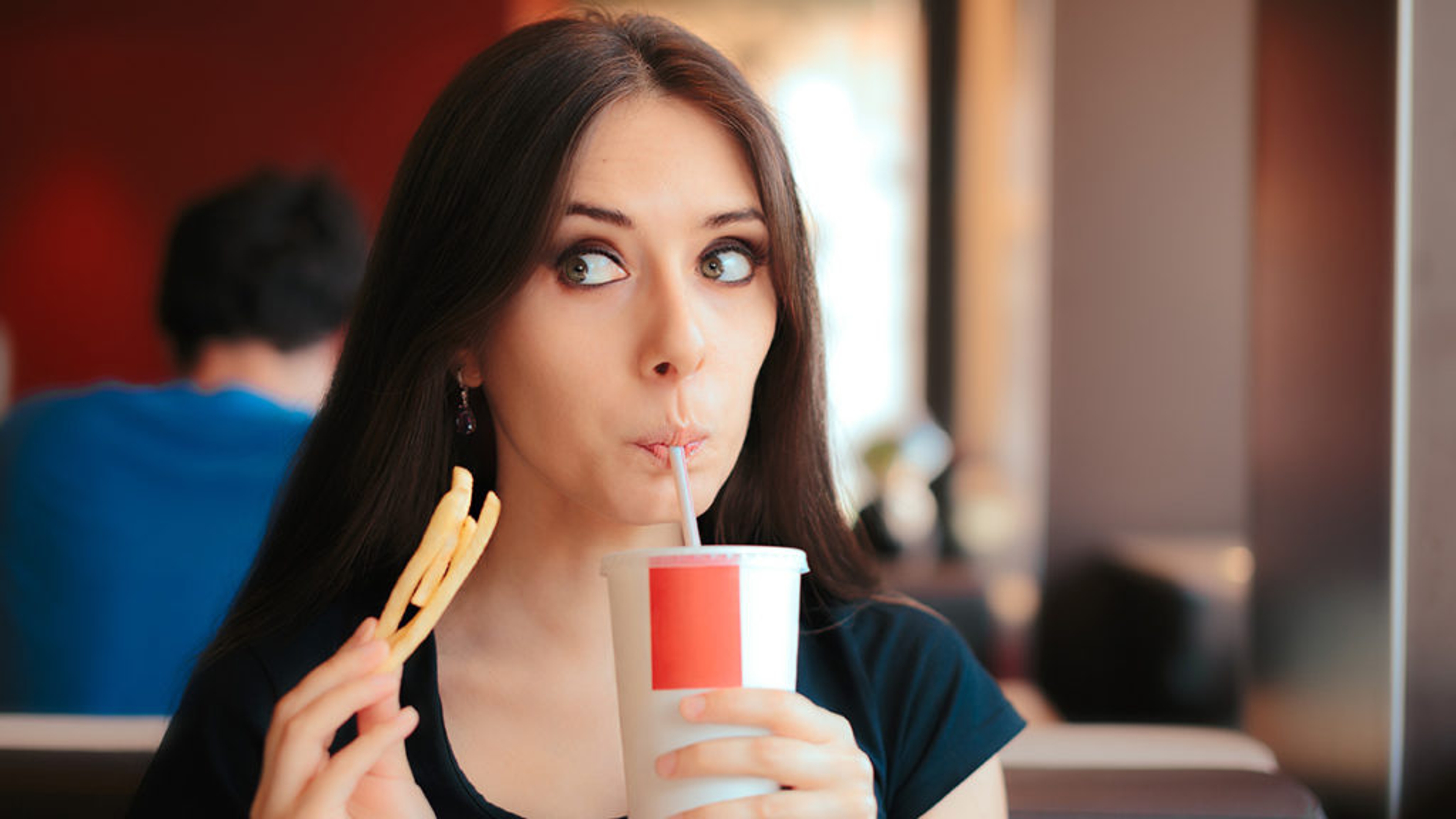 sweet and salty snacks woman eating french fries drinking soft drink