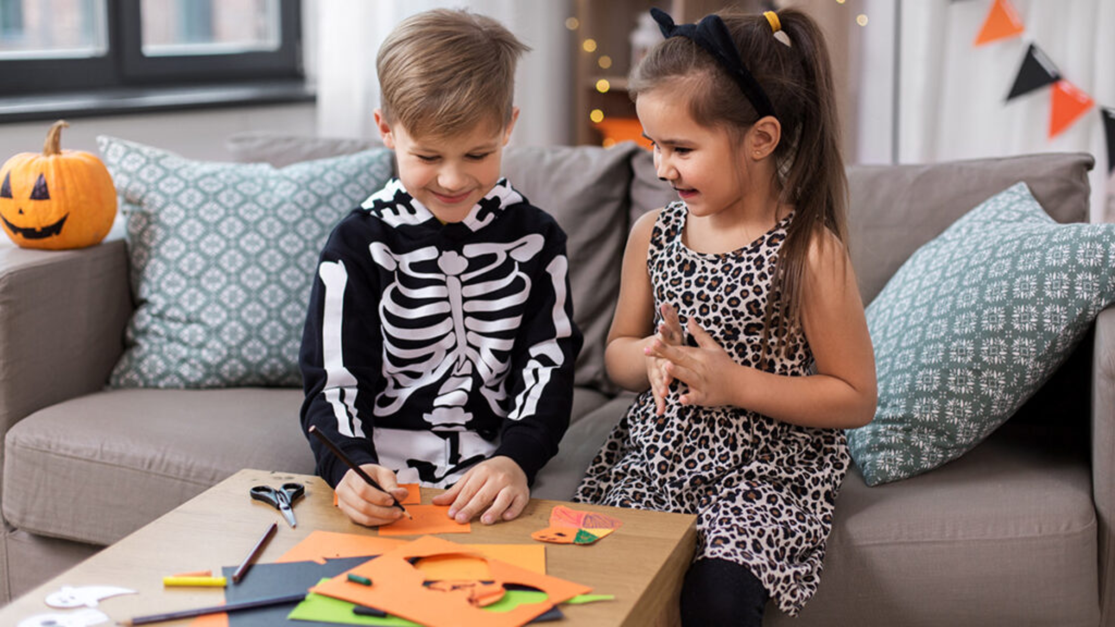 Two kids making boo bags for Halloween.