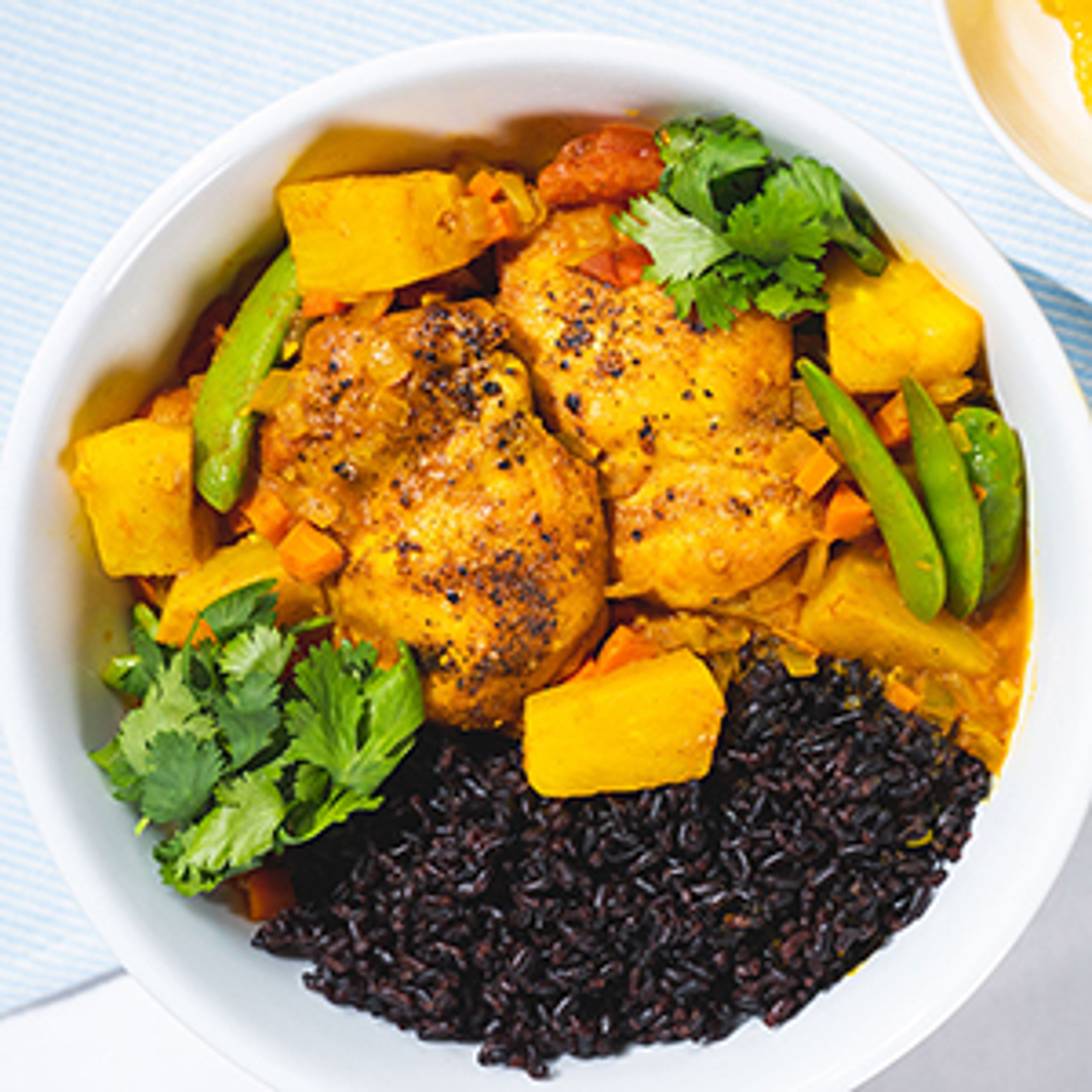Pineapple chicken curry in a bowl with wild rice and vegetables.