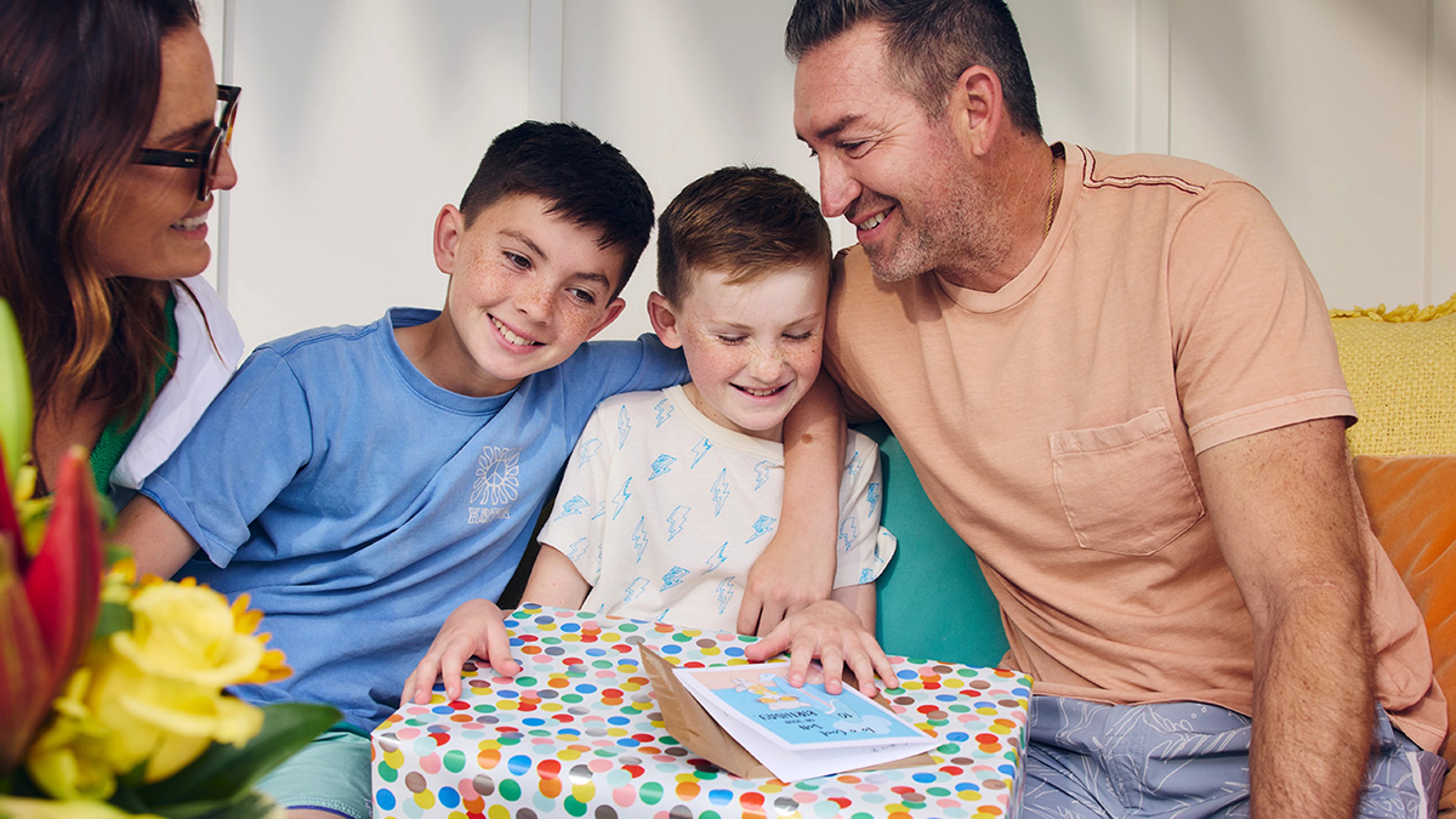 Two boys smiling while one opens a birthday gift.