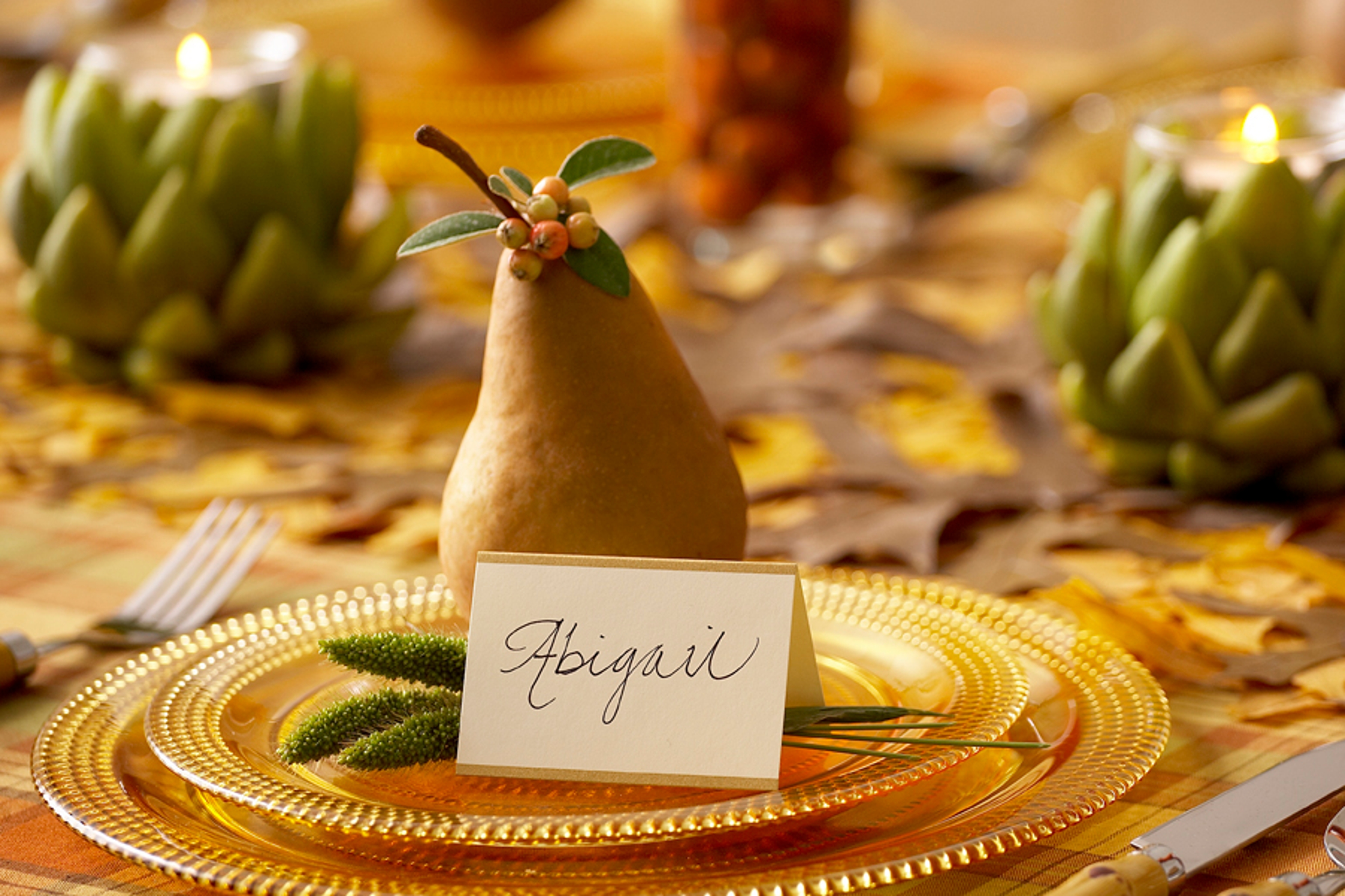 A photo of a pear tablescape with a pear on a gold plate with a name tag