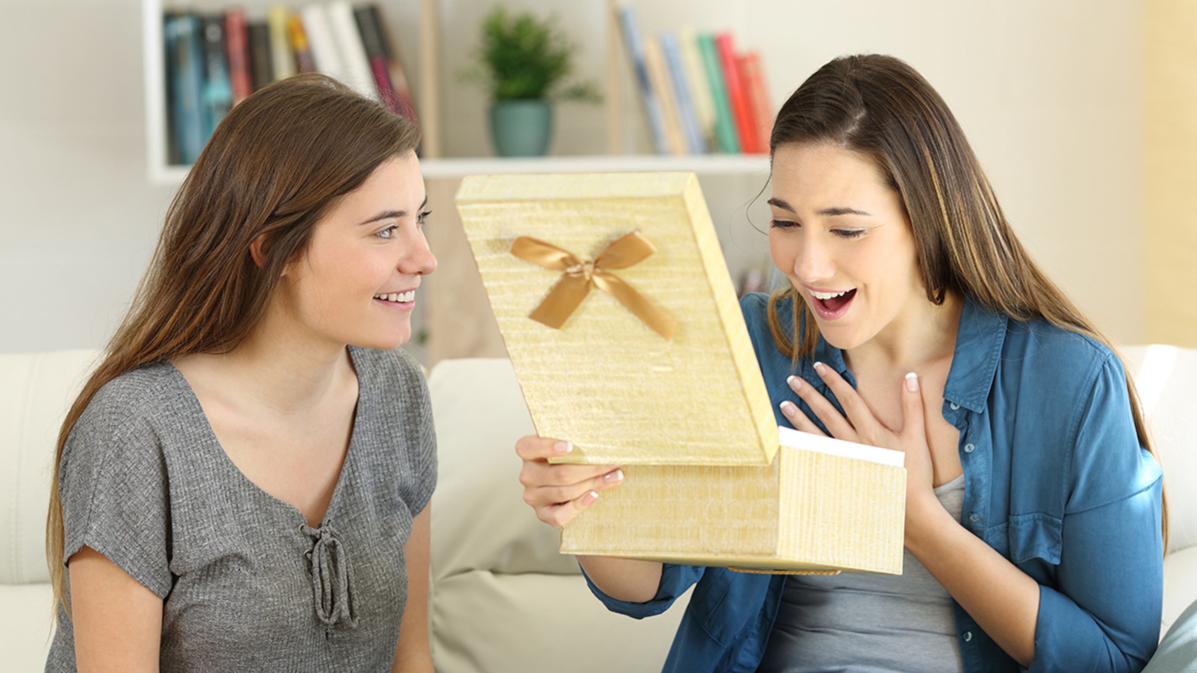 Two friends opening a gift box at home