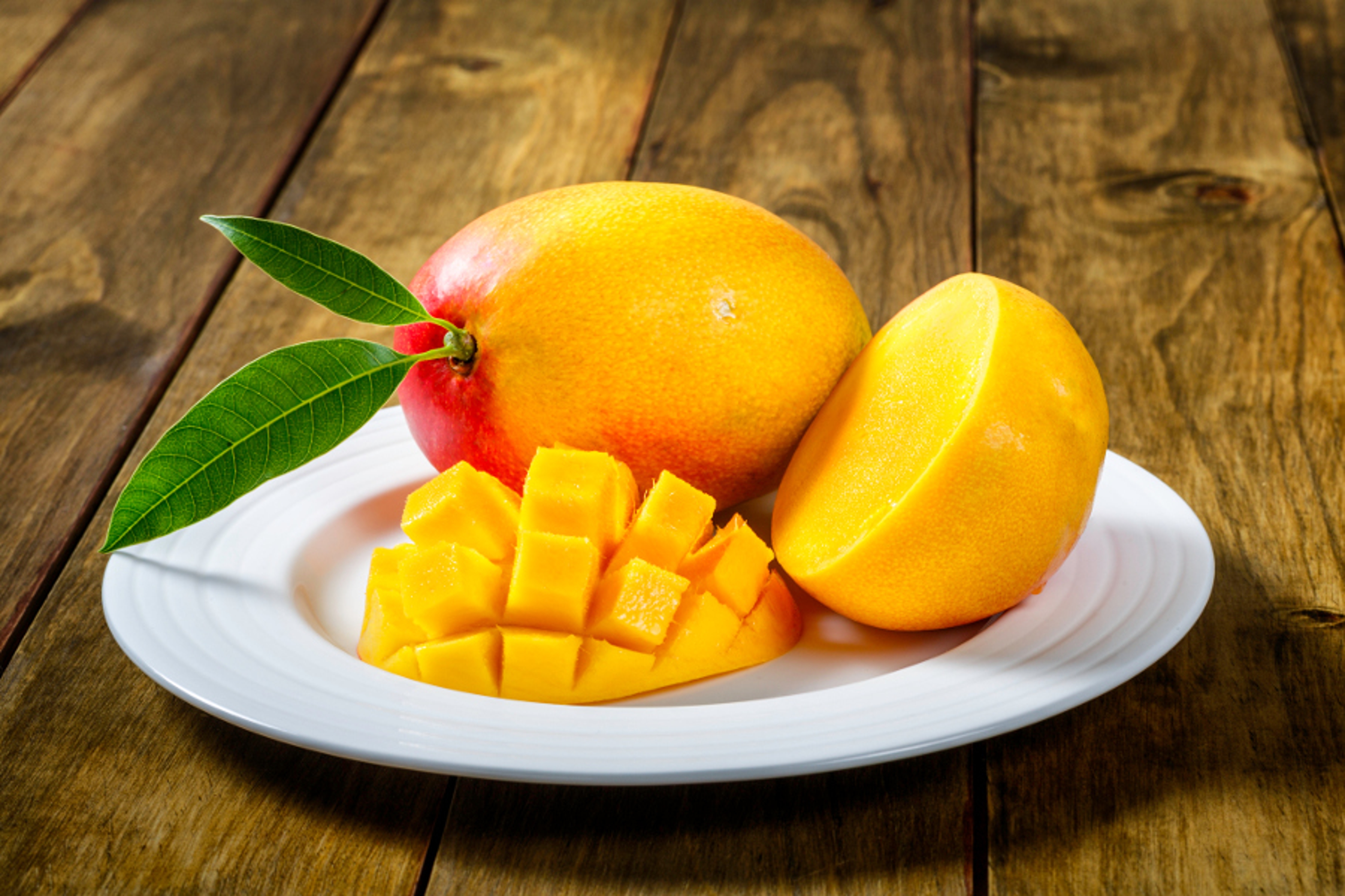 Article Cards Featured Image Tropical fruits   Sliced Mango on a plate ready for breakfast. All set over a wooden table. The mango belongs to the genus Mangifera and to the flowering plant family Anacardiaceae.  The mango is a juicy stone fruit and is native to south and southeast As