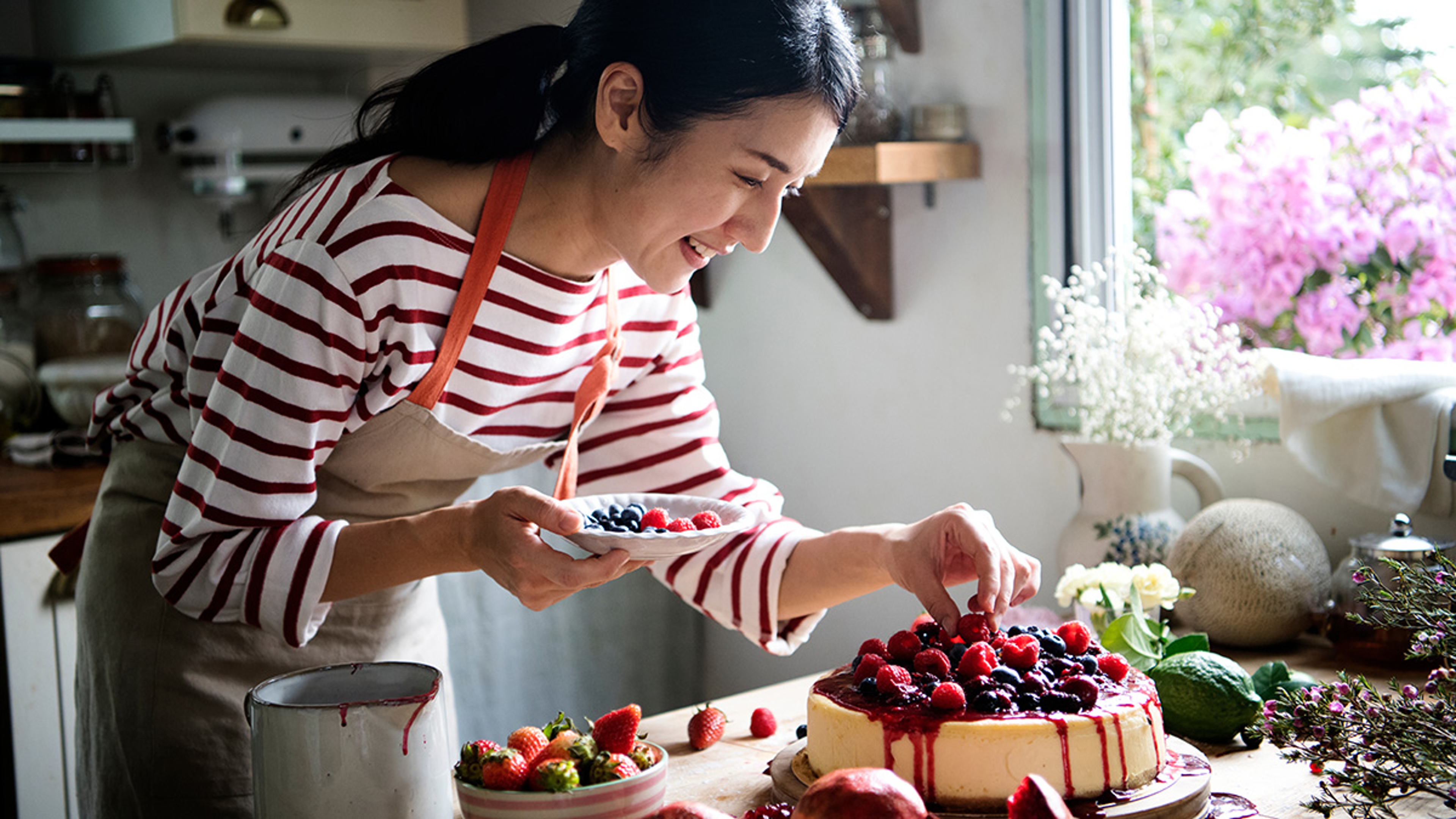 Woman putting berries on top of a cheesecake.