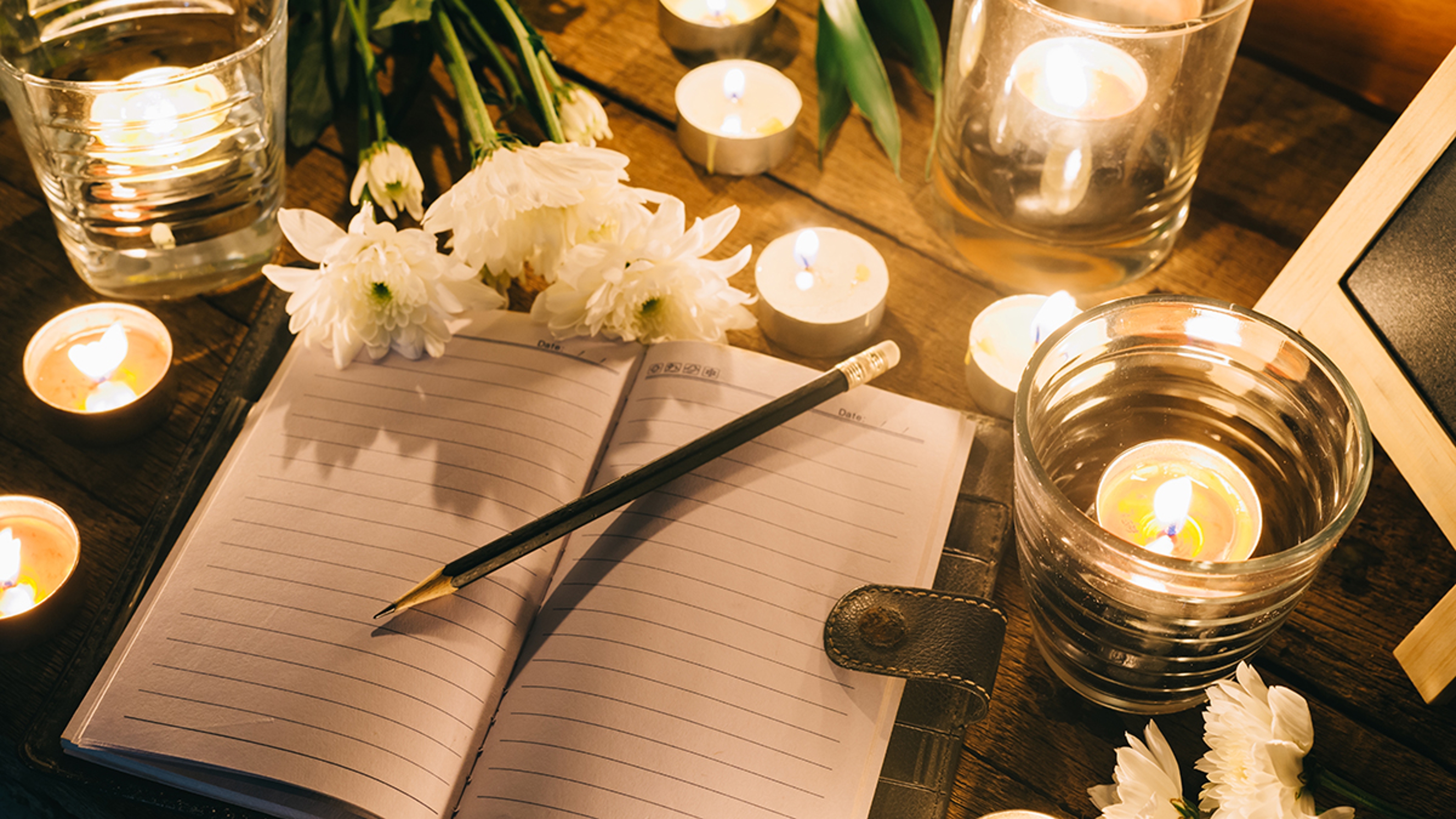 Article Cards Featured Image Writing in memory, pencil on empty notebook among candles