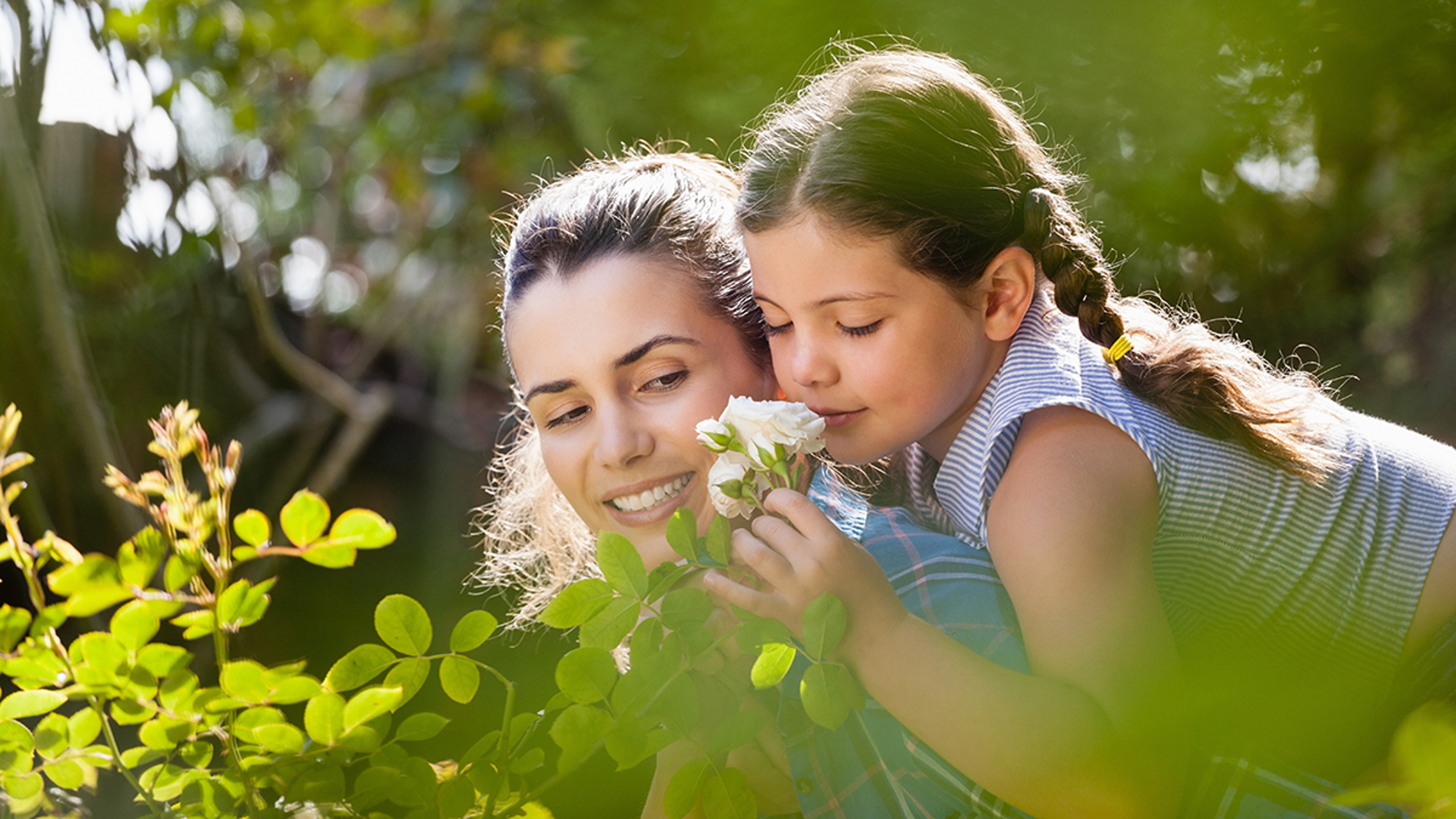 Article Cards Featured Image Girl smelling flowers while enjoying piggyback ride on mother