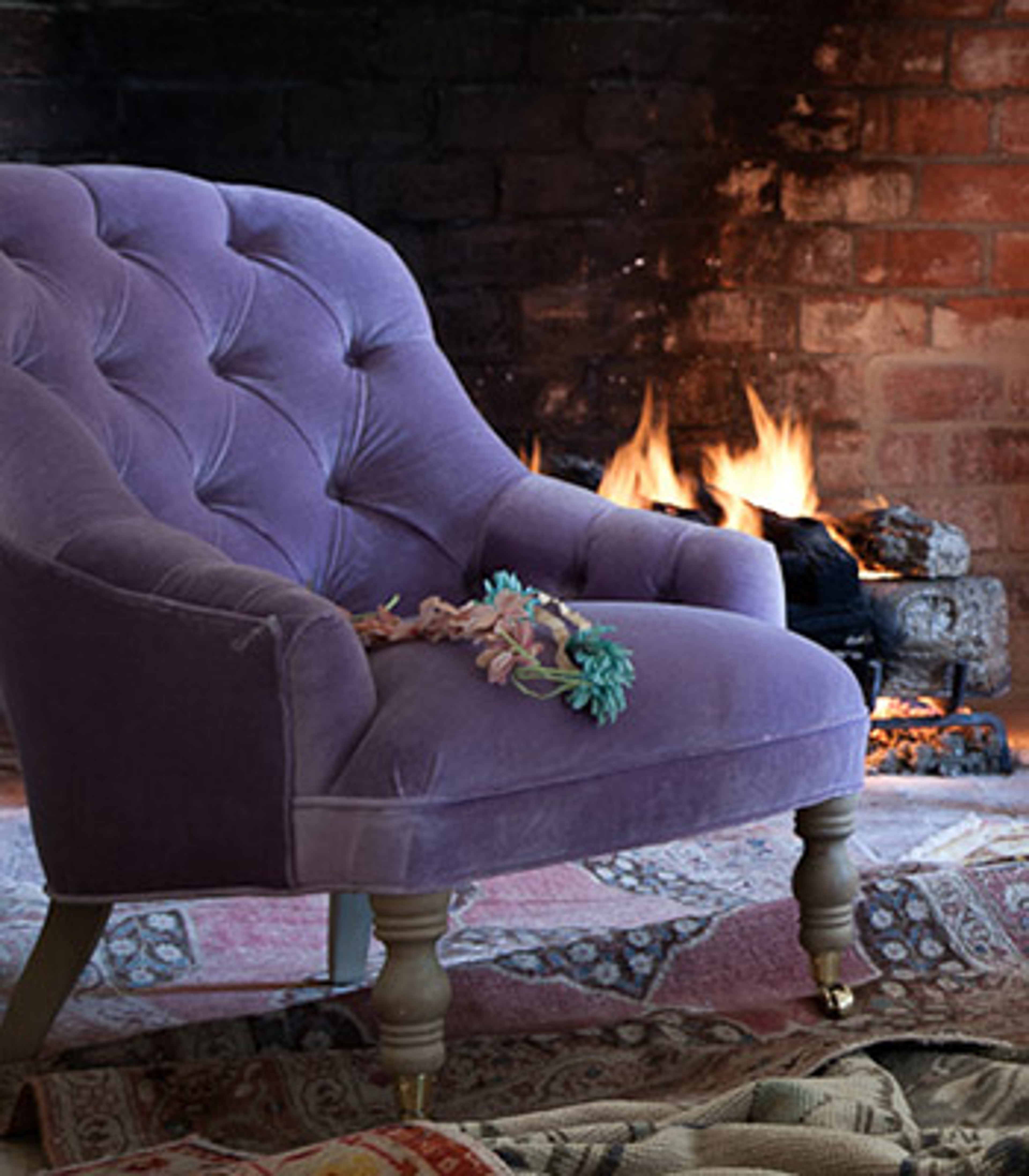 blush purple chair infront of a fireplace with dried flowers on it