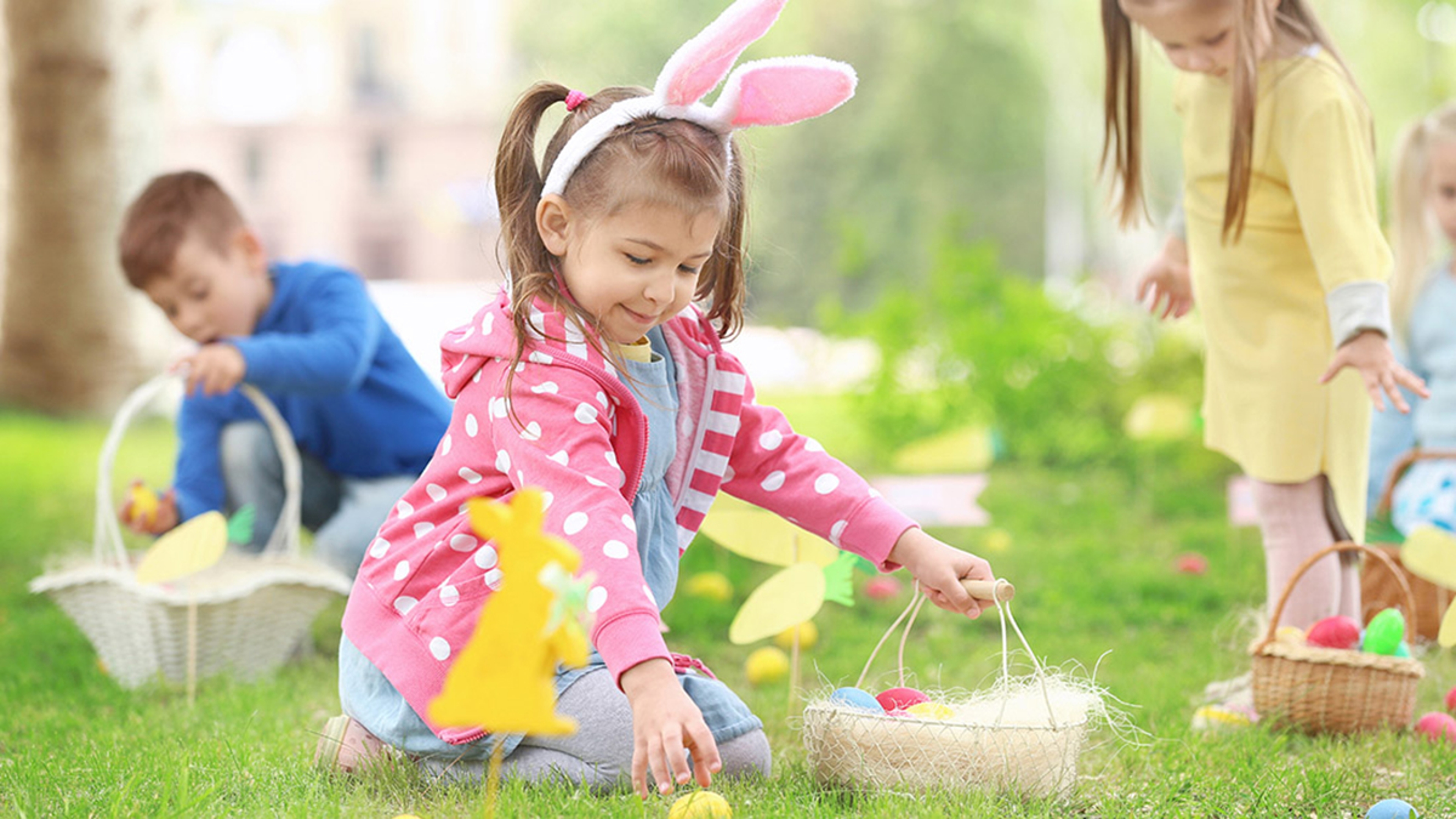 Easter egg hunt ideas with kids finding Easter eggs in the grass.