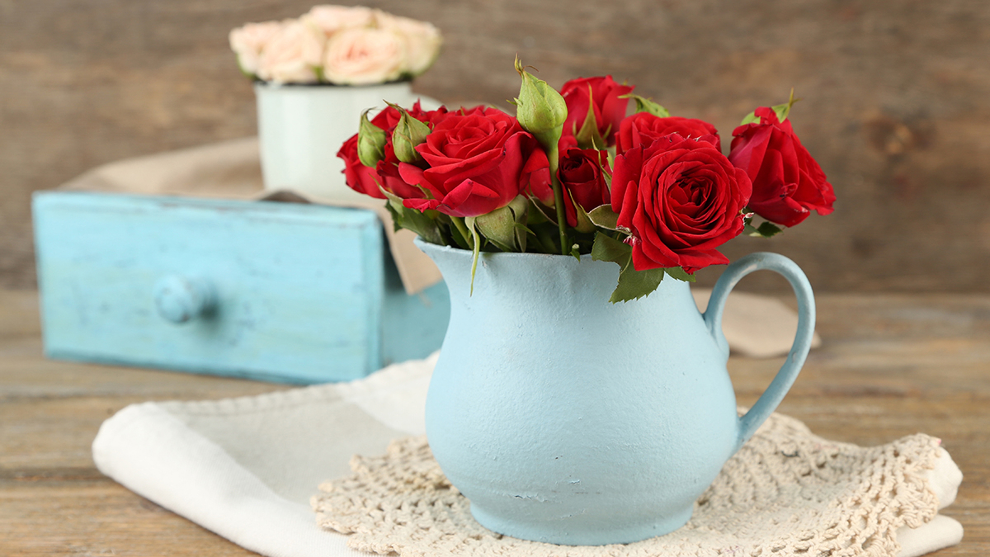 Bouquet of red roses in vase on wooden background