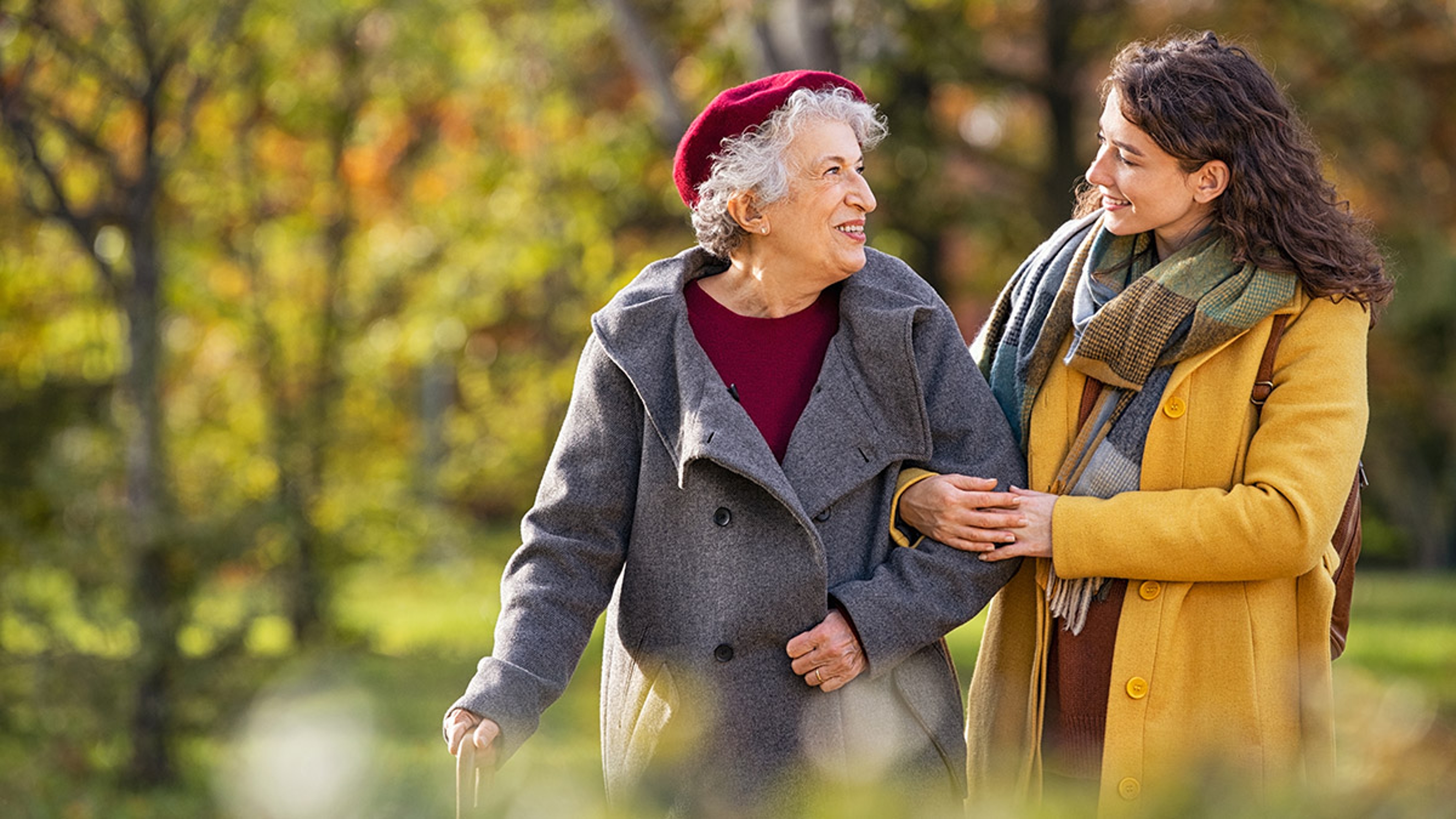 family caregiver with young woman taking walking with older woman