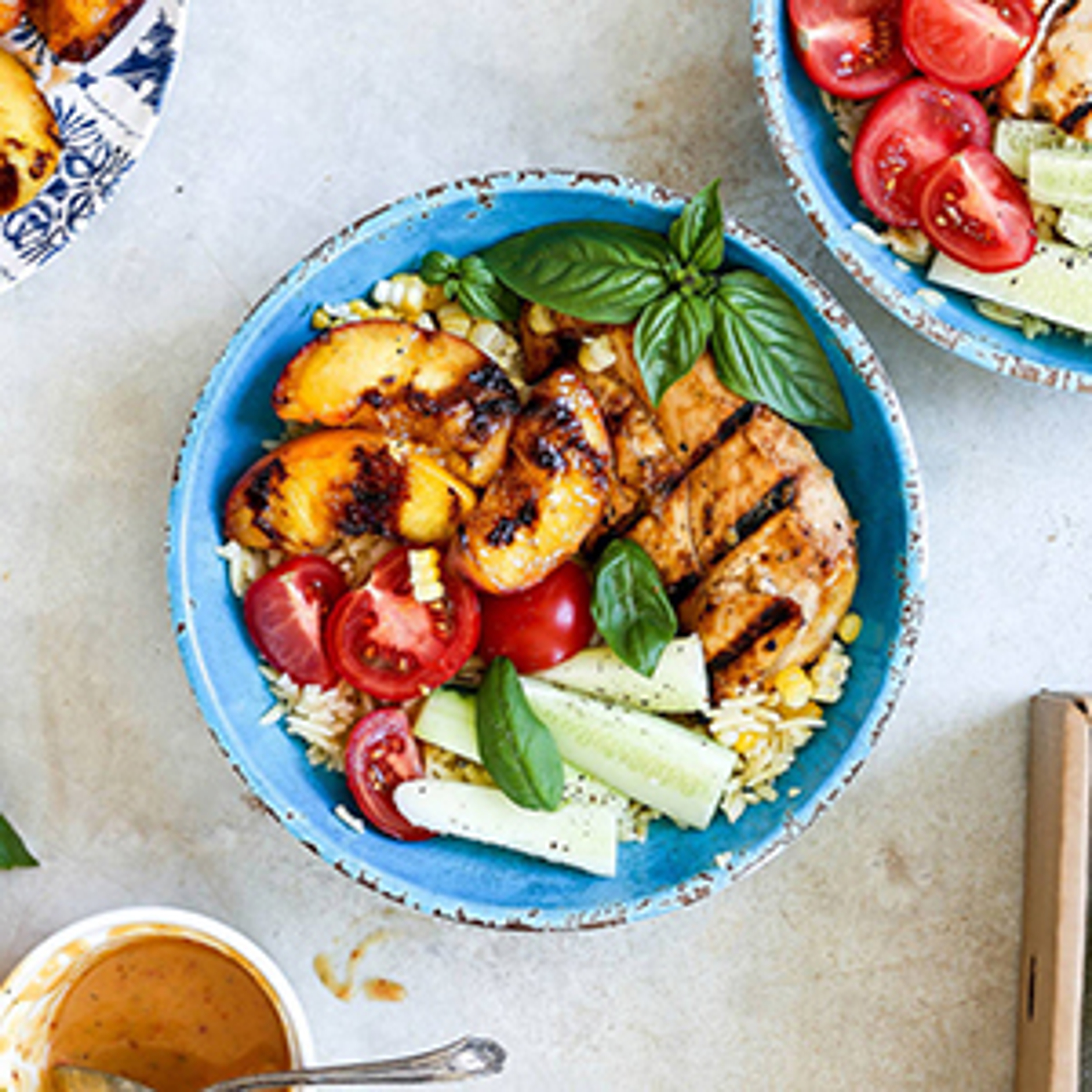 Bowl of rice topped with grilled peaches, grilled chicken, and vegetables.