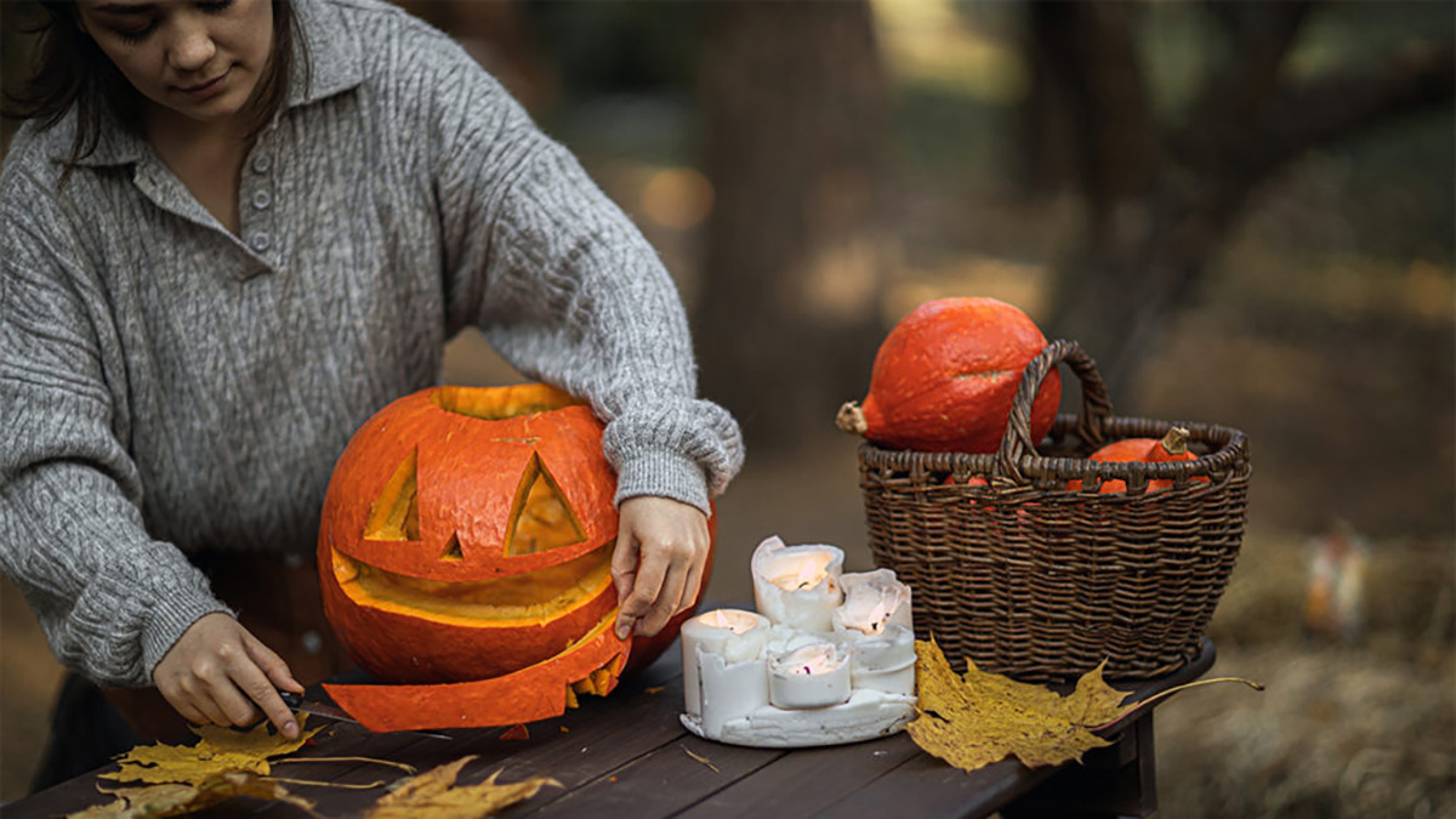 Woman carving a jack o lantern outside.