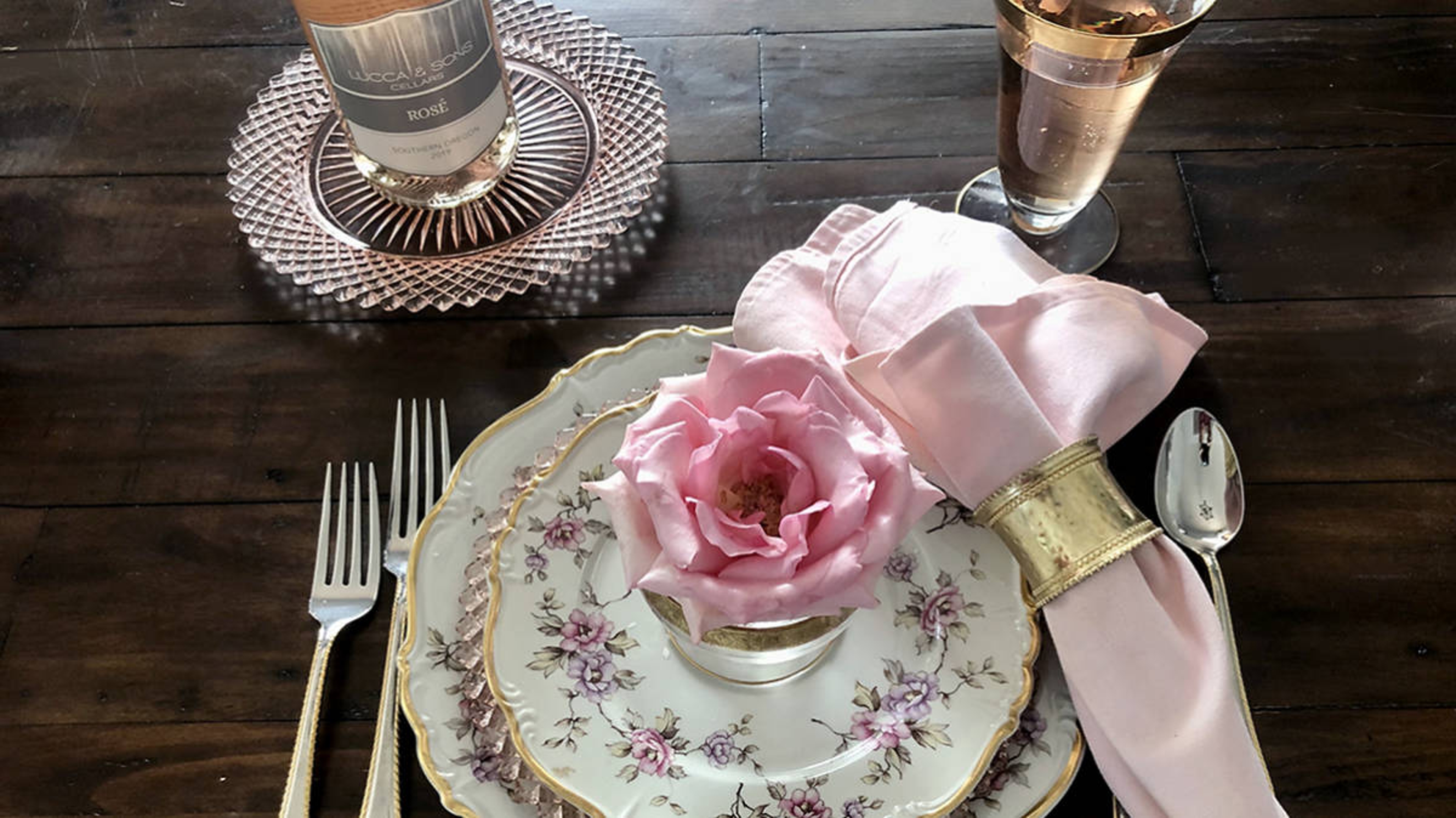 photo of waxed roses with a waxed rose in a table setting and a bottle of rosé