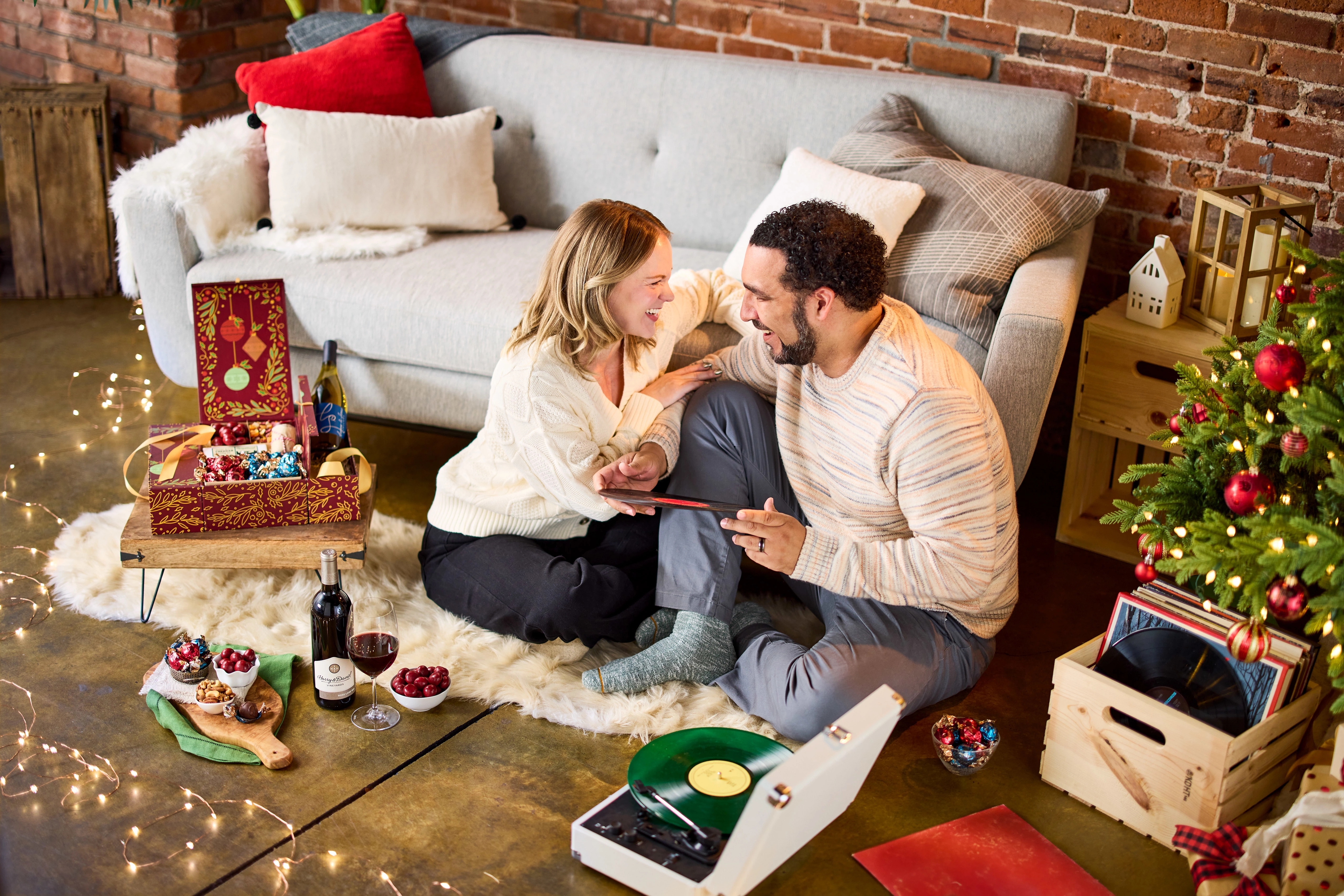 Couple sitting on floor exchanging Christmas presents.