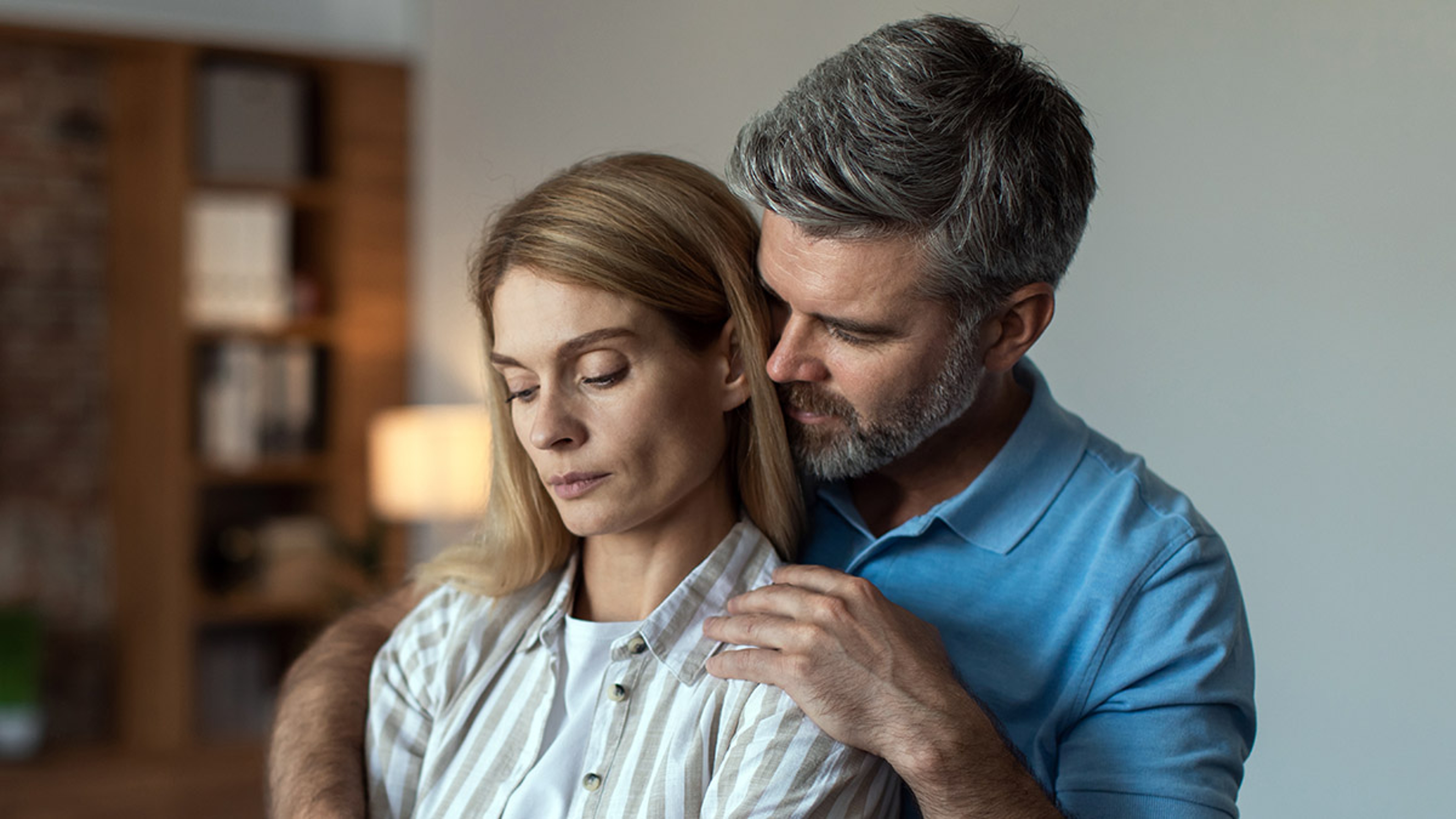 Article Cards Featured Image Serious mature caucasian male with beard hugs, calm offended female in living room interior, free space