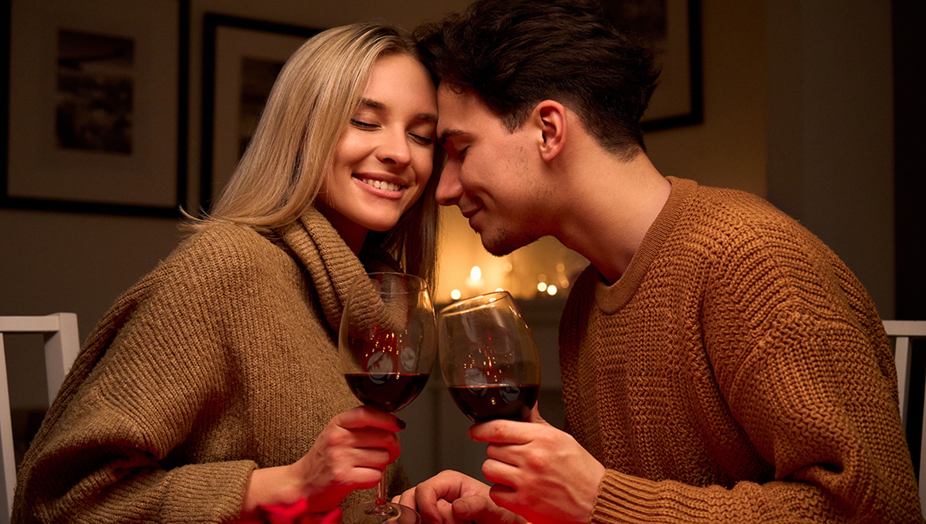 Happy couple in love clinking glasses drinking red wine having romantic dinner.