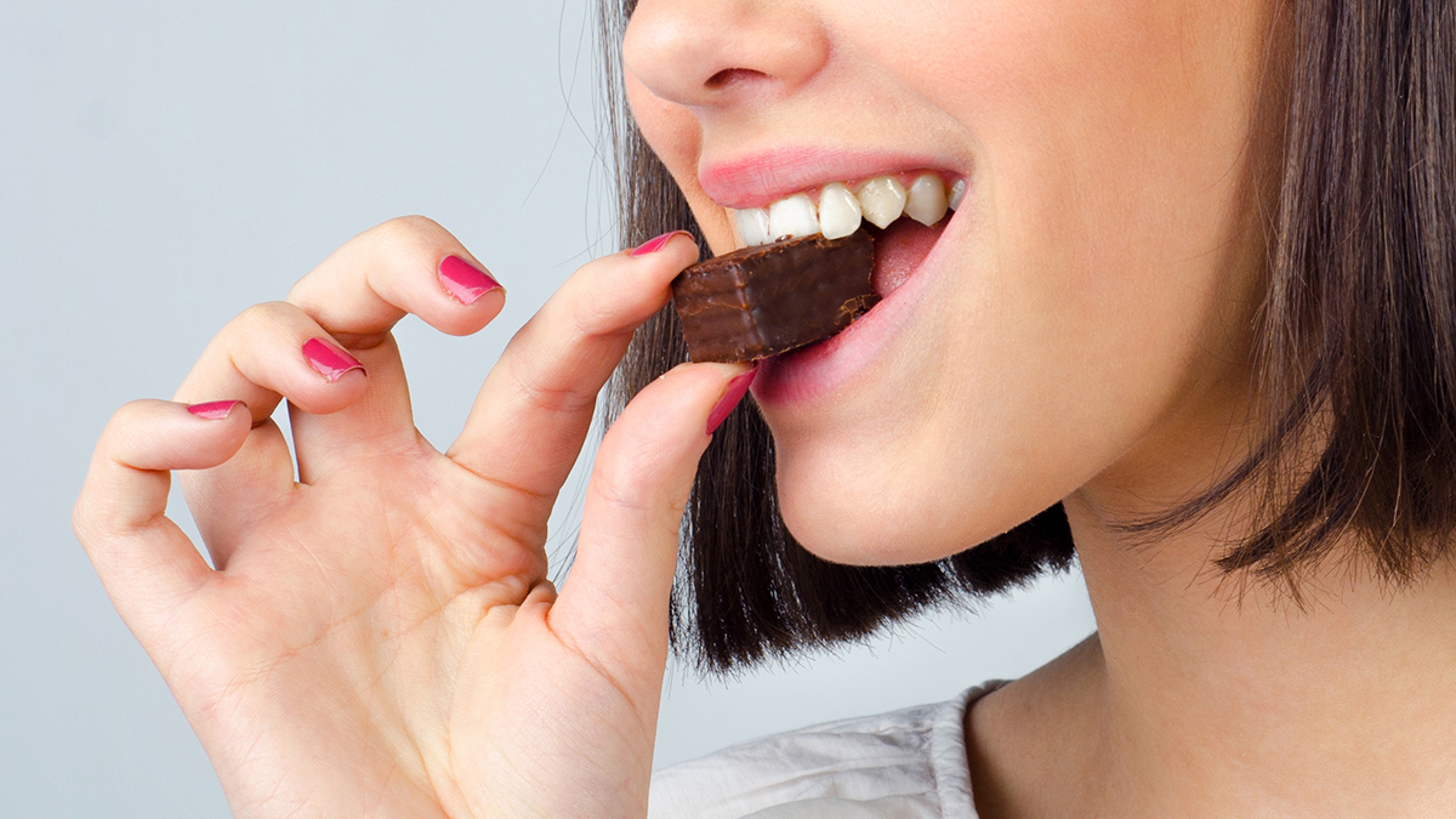 Closeup of a woman eating a chocolate cookie.