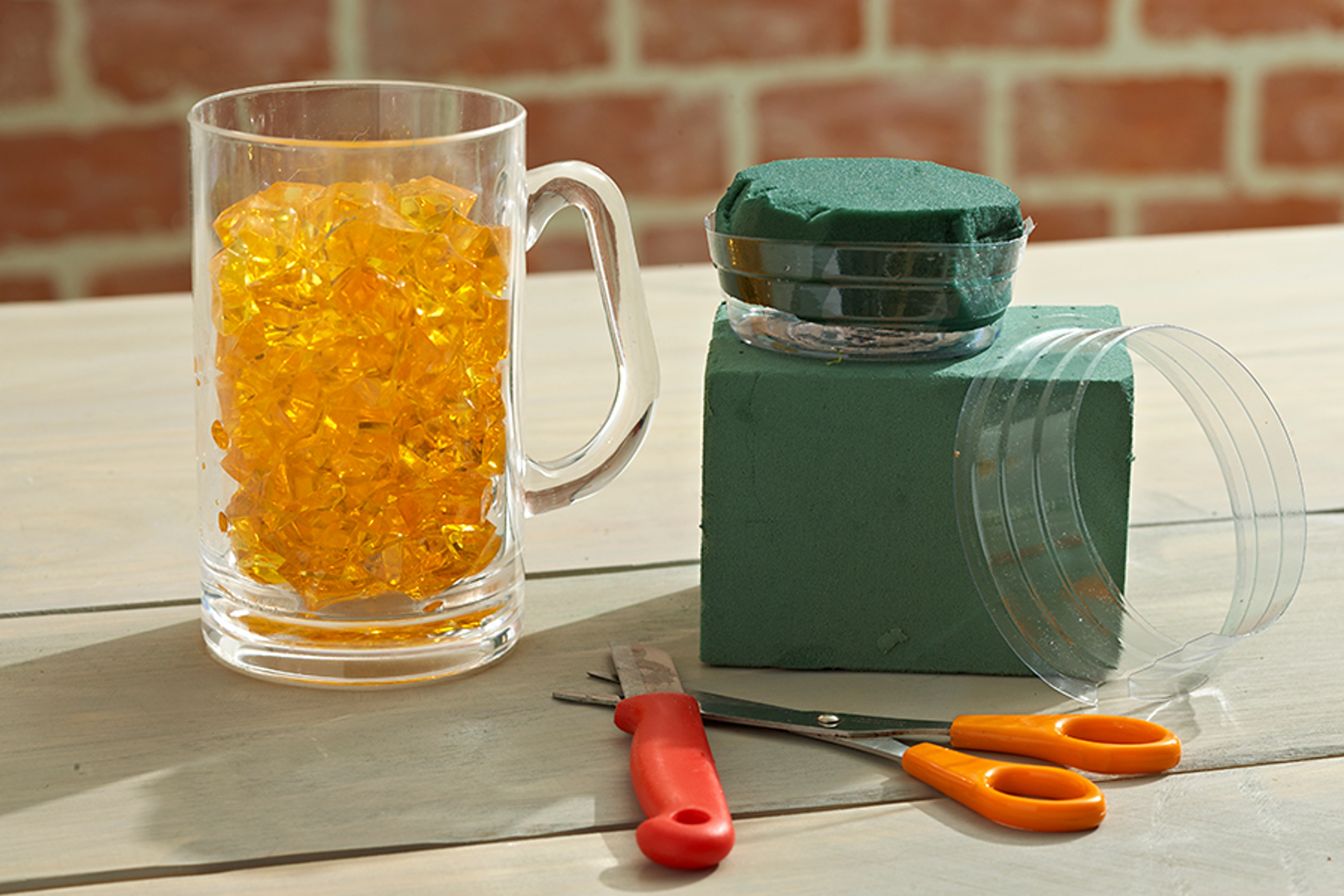 Beer mug full of acrylic gems next to flower crafting items.