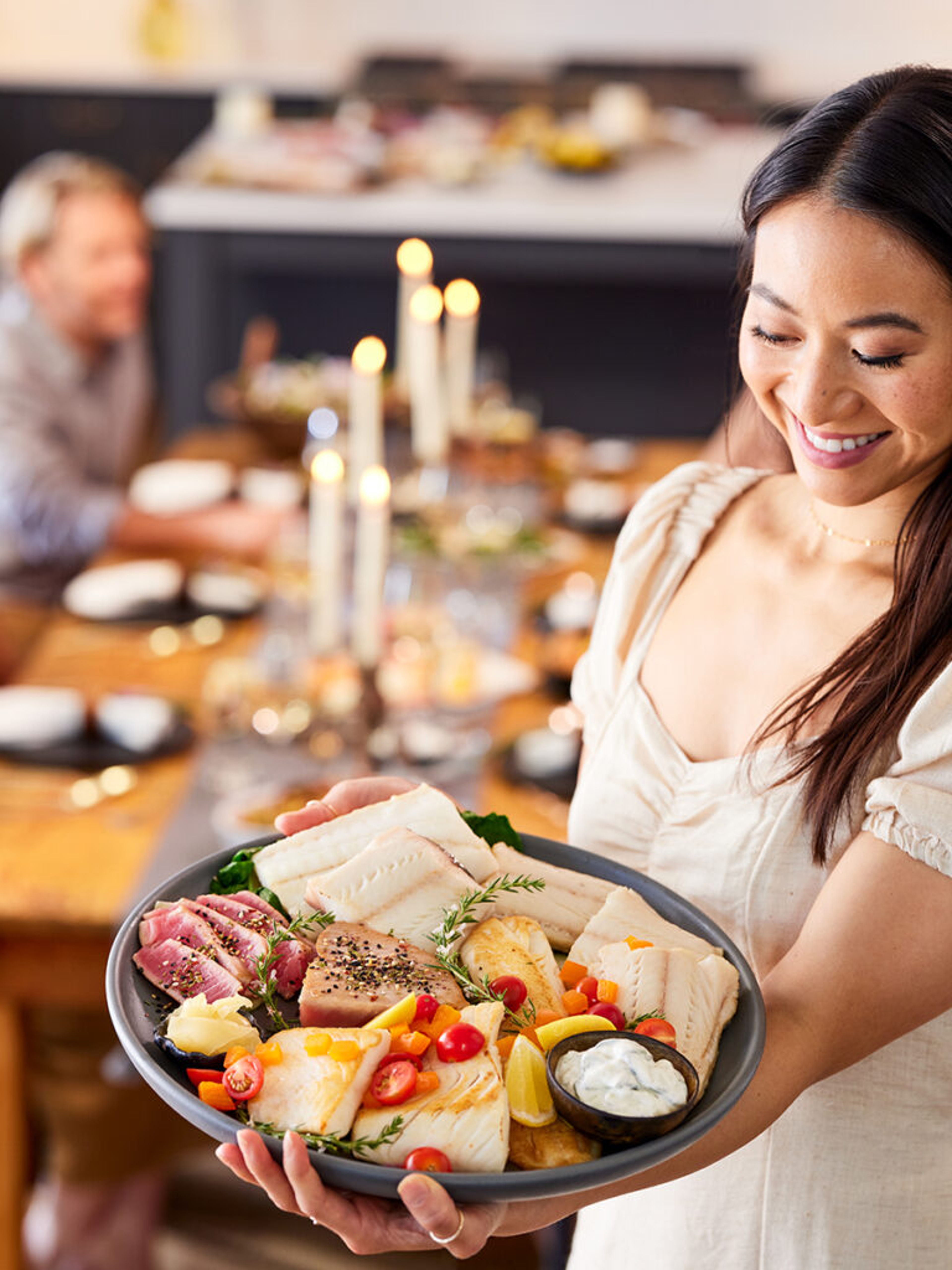 Woman holding a platter of cooked seafood.